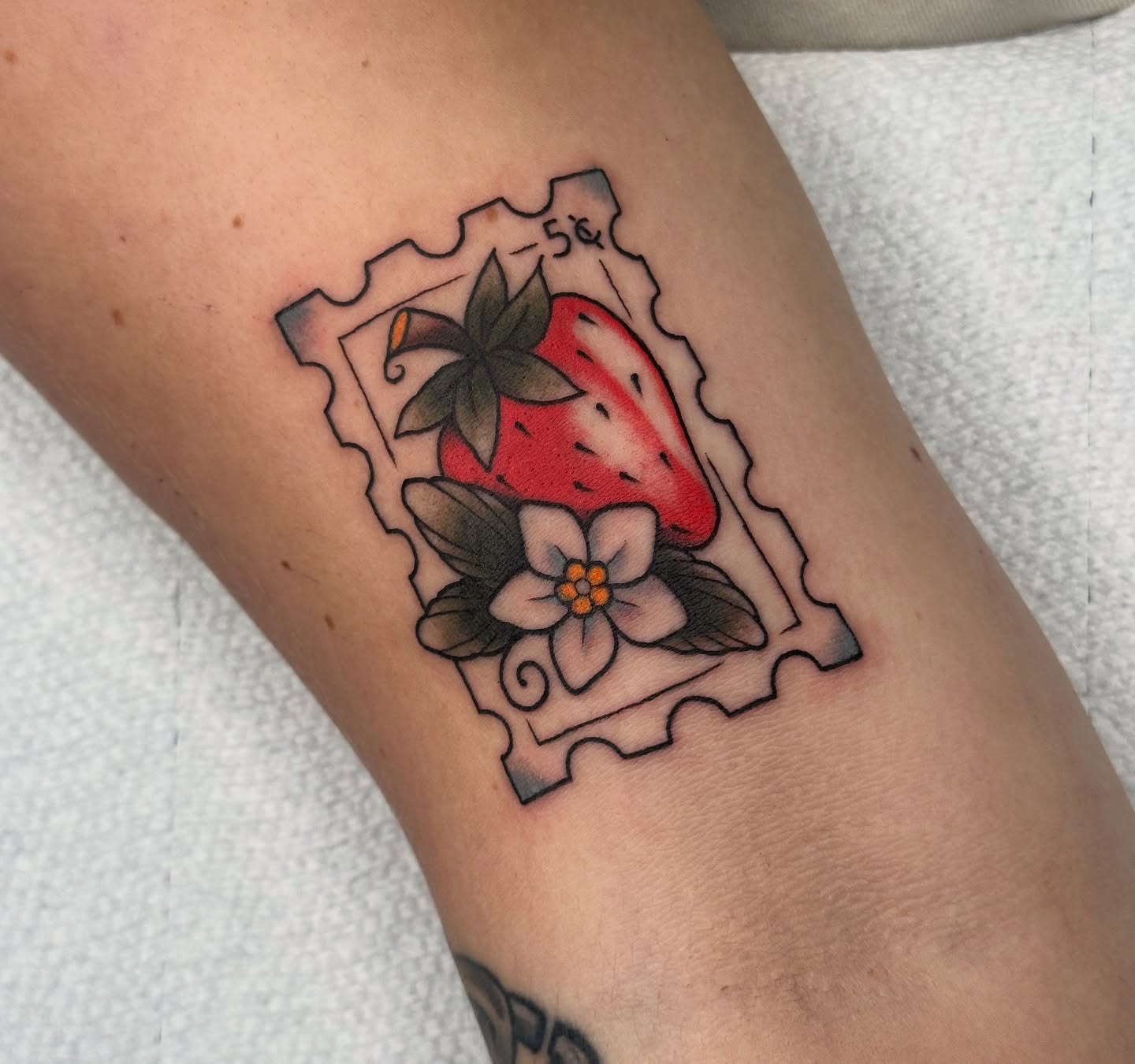 Strawberry and flower American traditional tattoo on the forearm by Caity