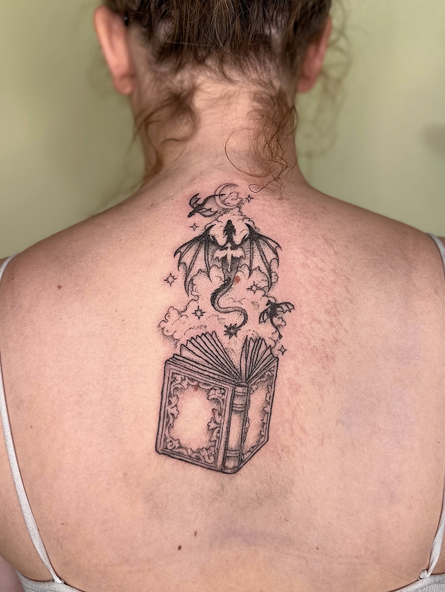 Book with dragon realism tattoo on the back by kenzie hunter