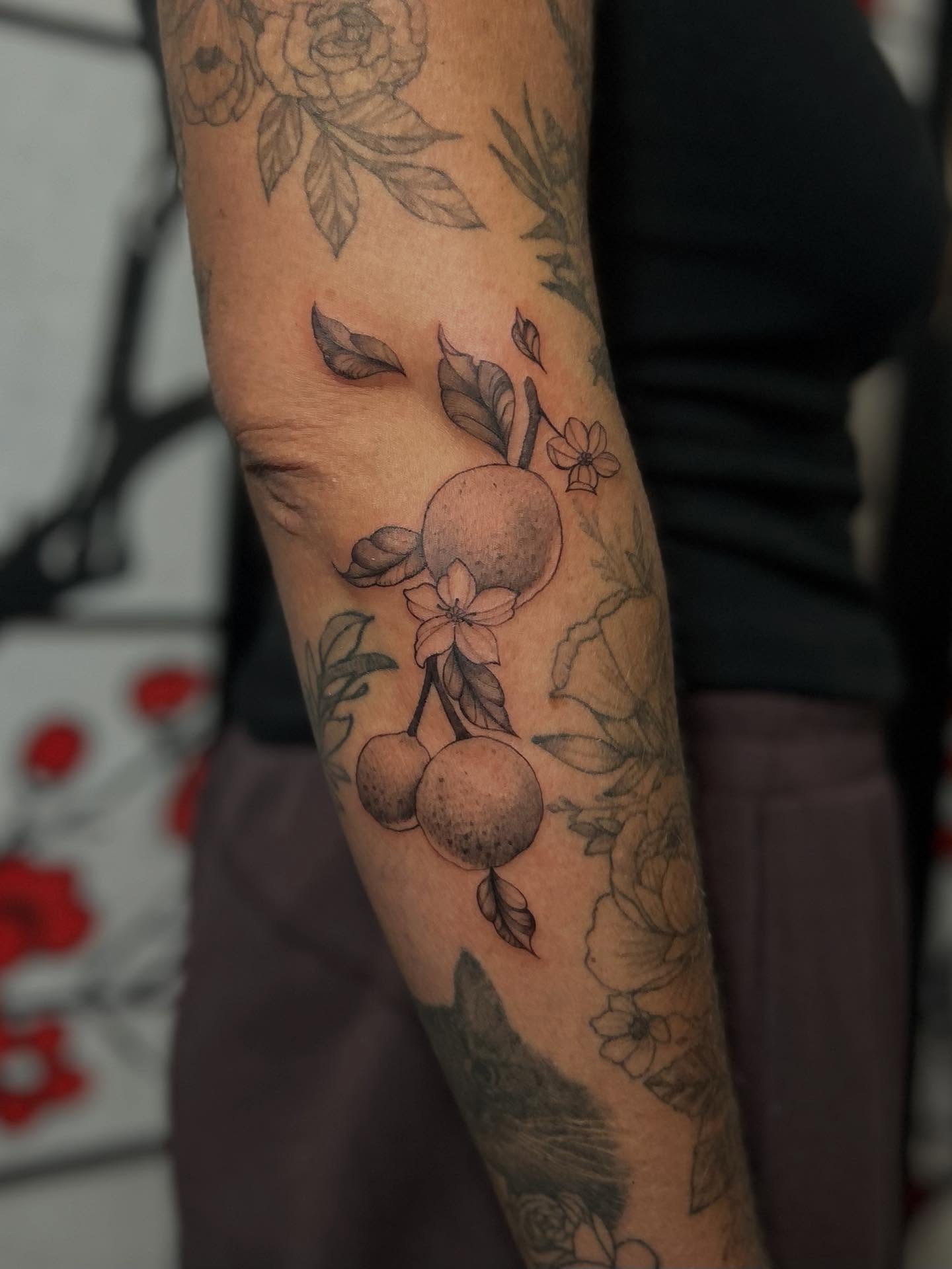 Fruit and floral arrangement black and grey tattoo on the forearm by Chloe