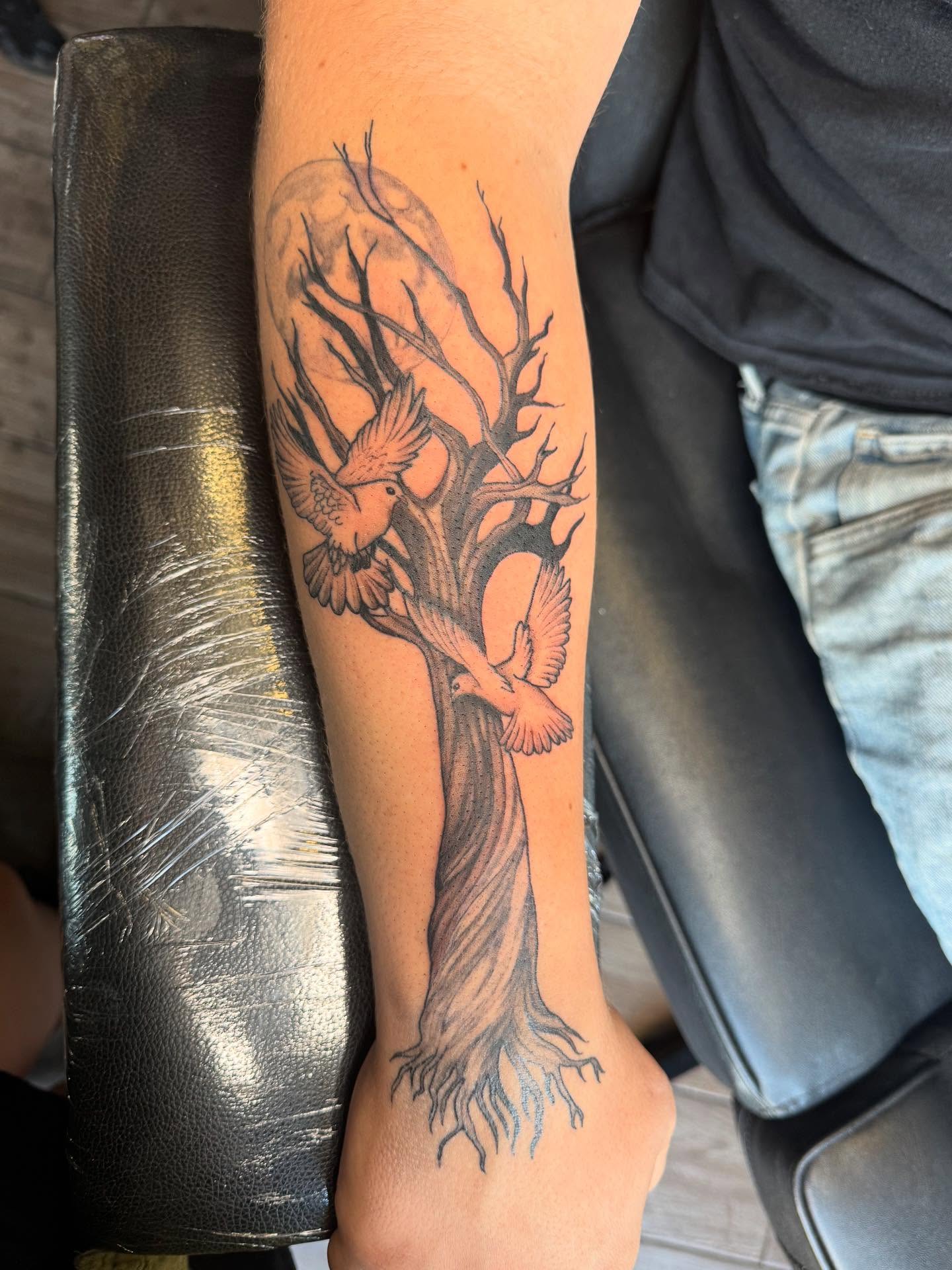 Tree with birds black and grey tattoo on the forearm by Mickey