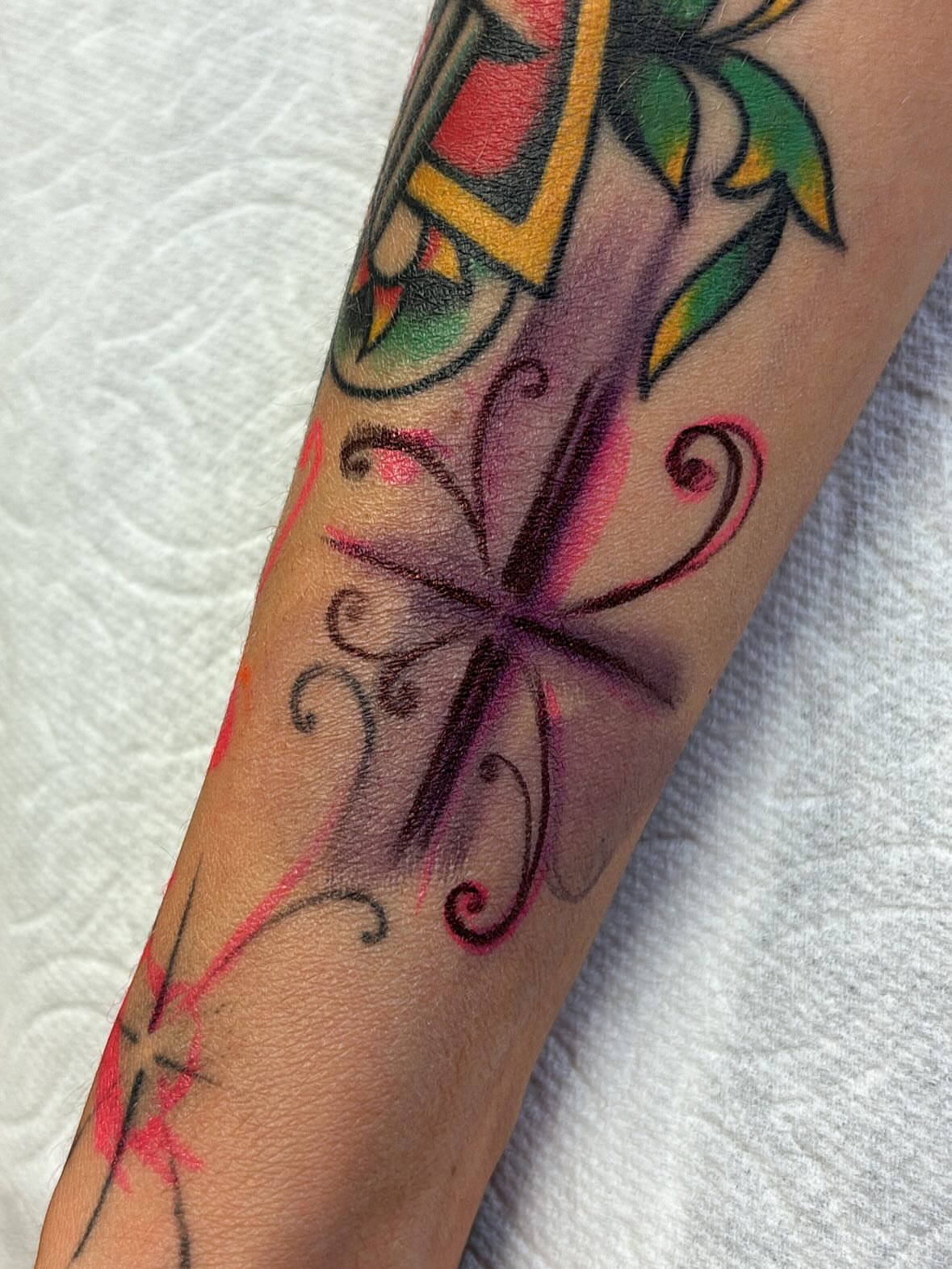 Cross with floral swirls American traditional tattoo on the forearm by Storm