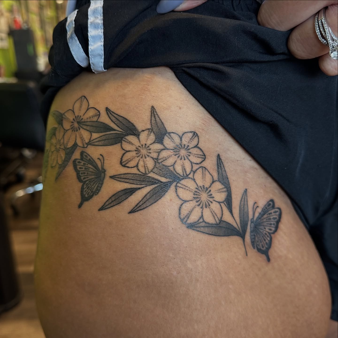 Flowers and butterflies black and grey tattoo on the thigh by Lauren Howard Tattoos