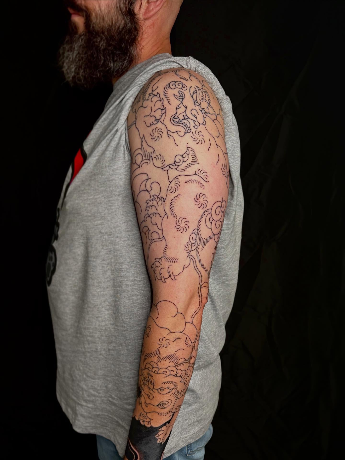 Lion and clouds black and grey tattoo on the upper arm by Zach Hendrickson