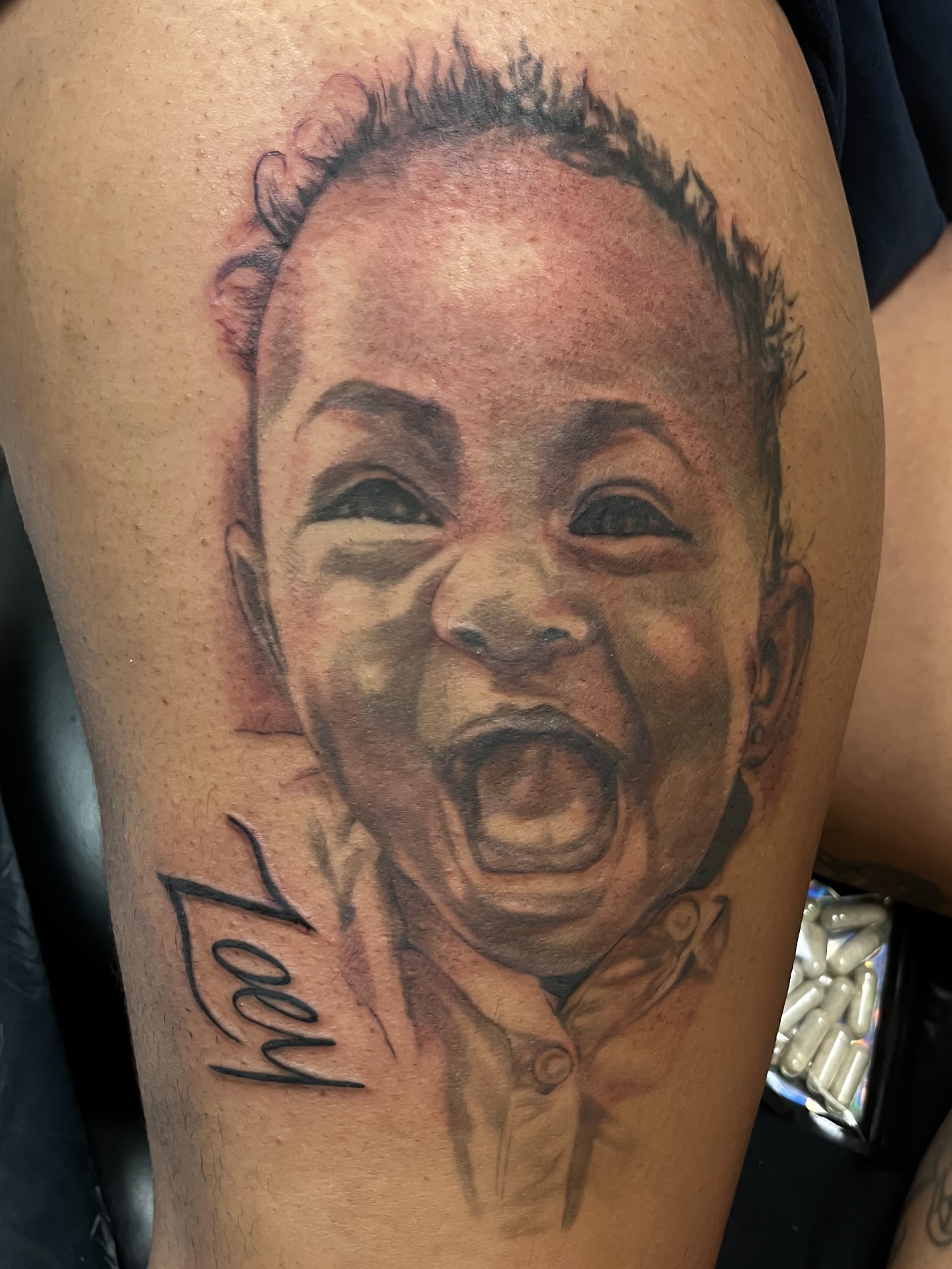 Baby portrait realism tattoo on the thigh by Quinten Harper