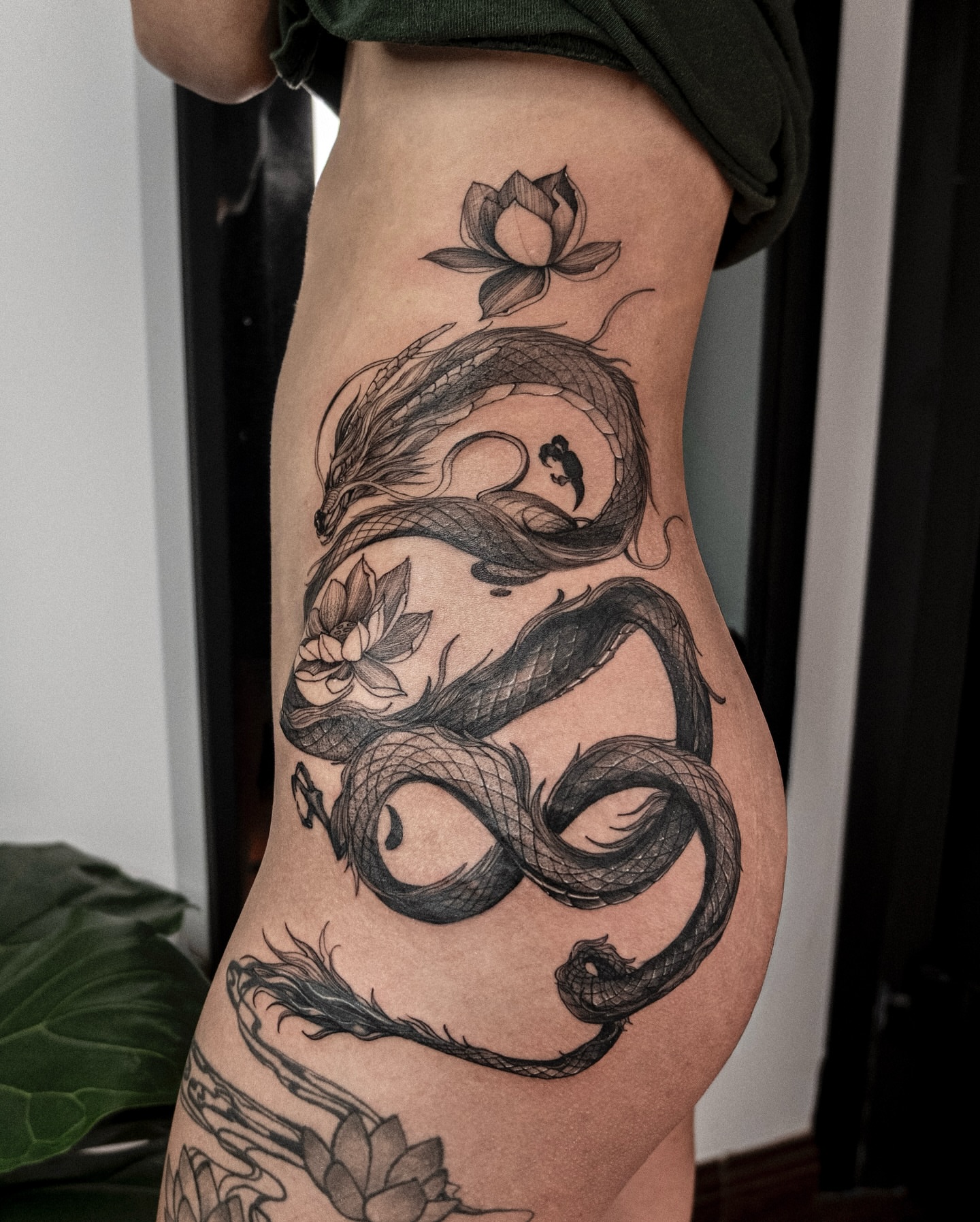 Snake and lotus black and grey tattoo on the thigh by Wong Lee