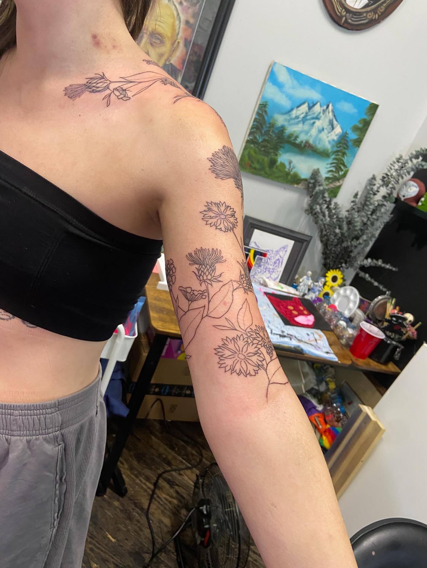 Floral arrangement black and grey tattoo on the upper arm by Dont Worry About It