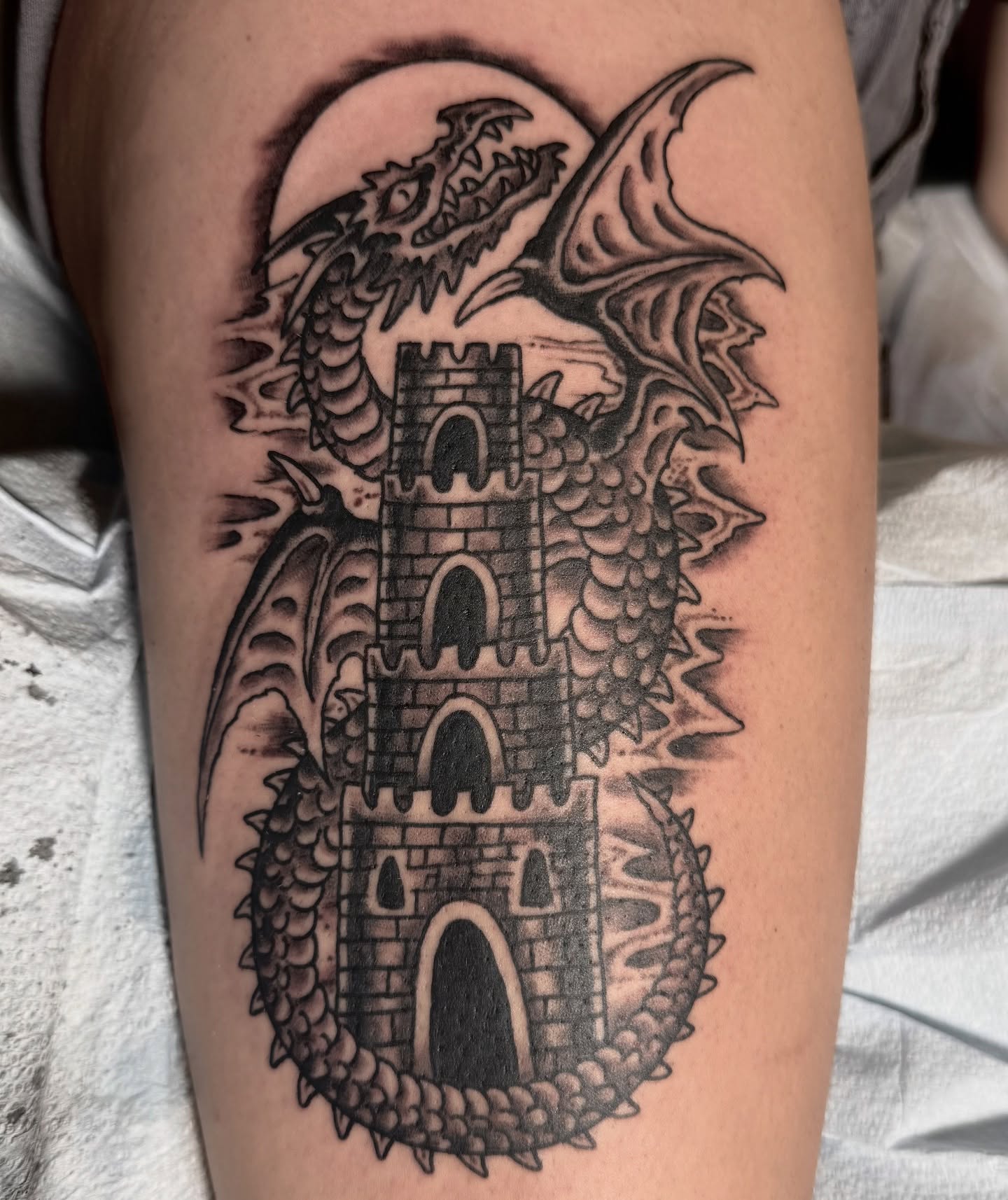 Castle and dragon black and grey tattoo on the thigh by Jesse Swanson, Santa Rosa, California