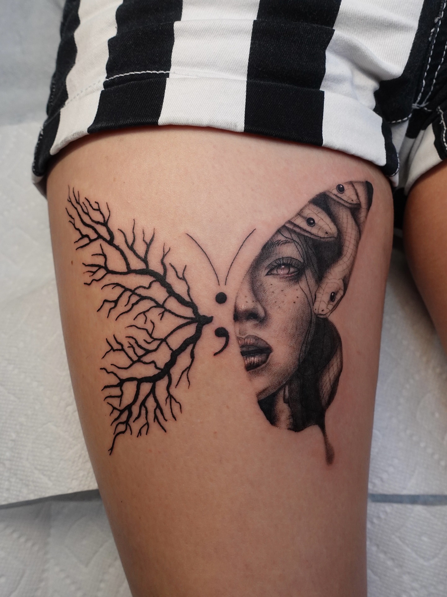Woman's face with tree dotwork tattoo on the thigh by Tat by Brendan