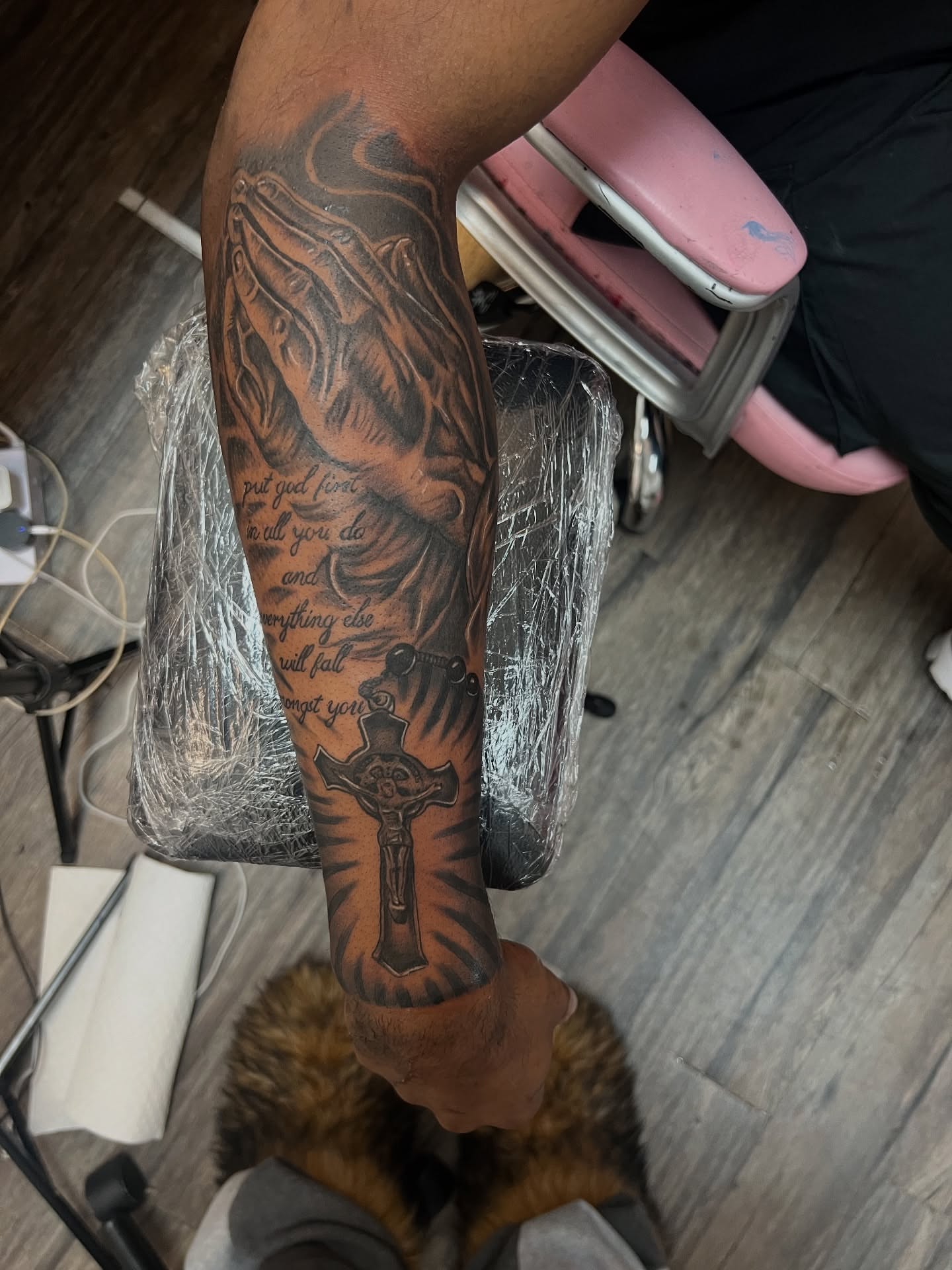 Praying hands with cross black and grey tattoo on the forearm by Bri Tatted That