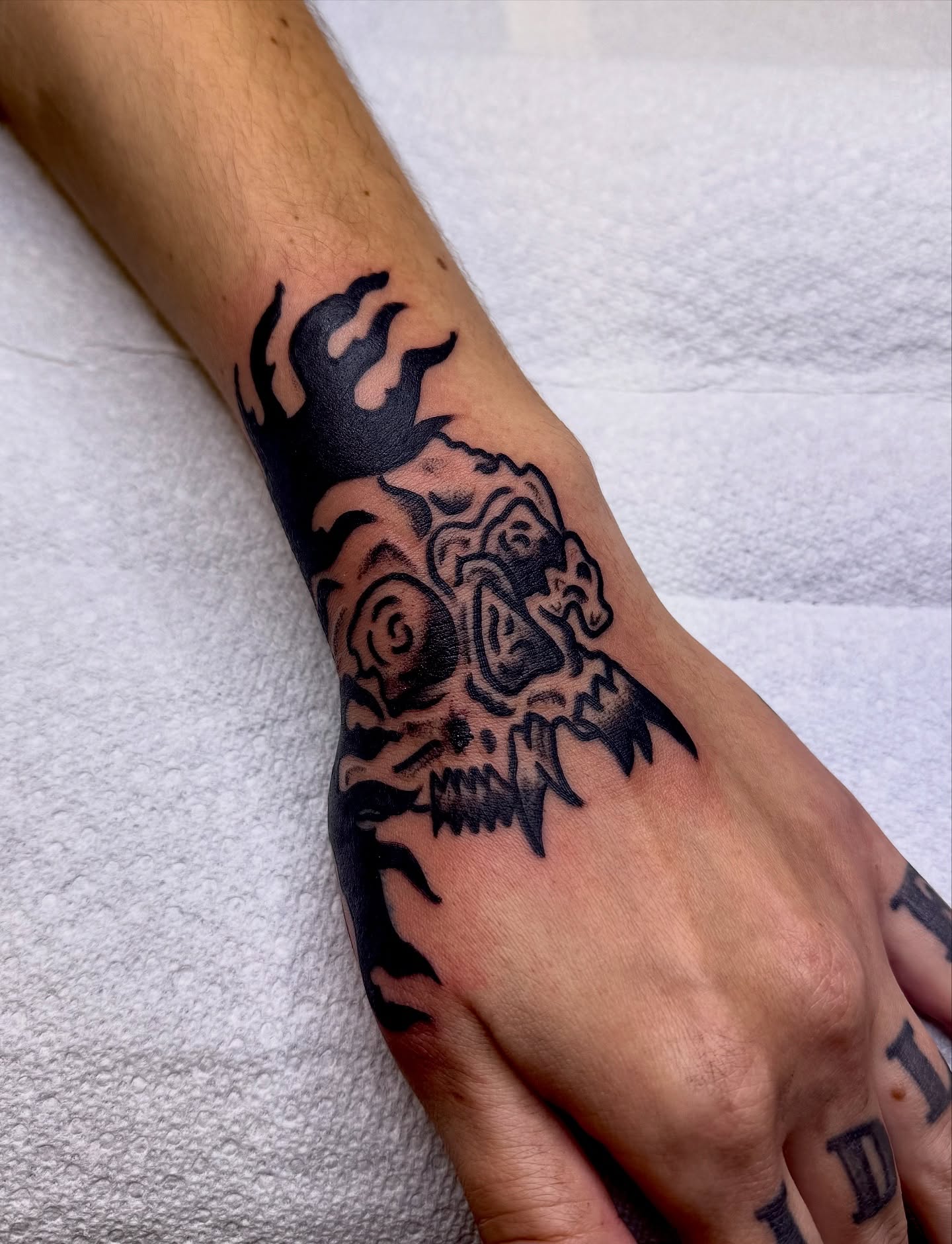 Skull and flames black and grey tattoo on the forearm by Brandon