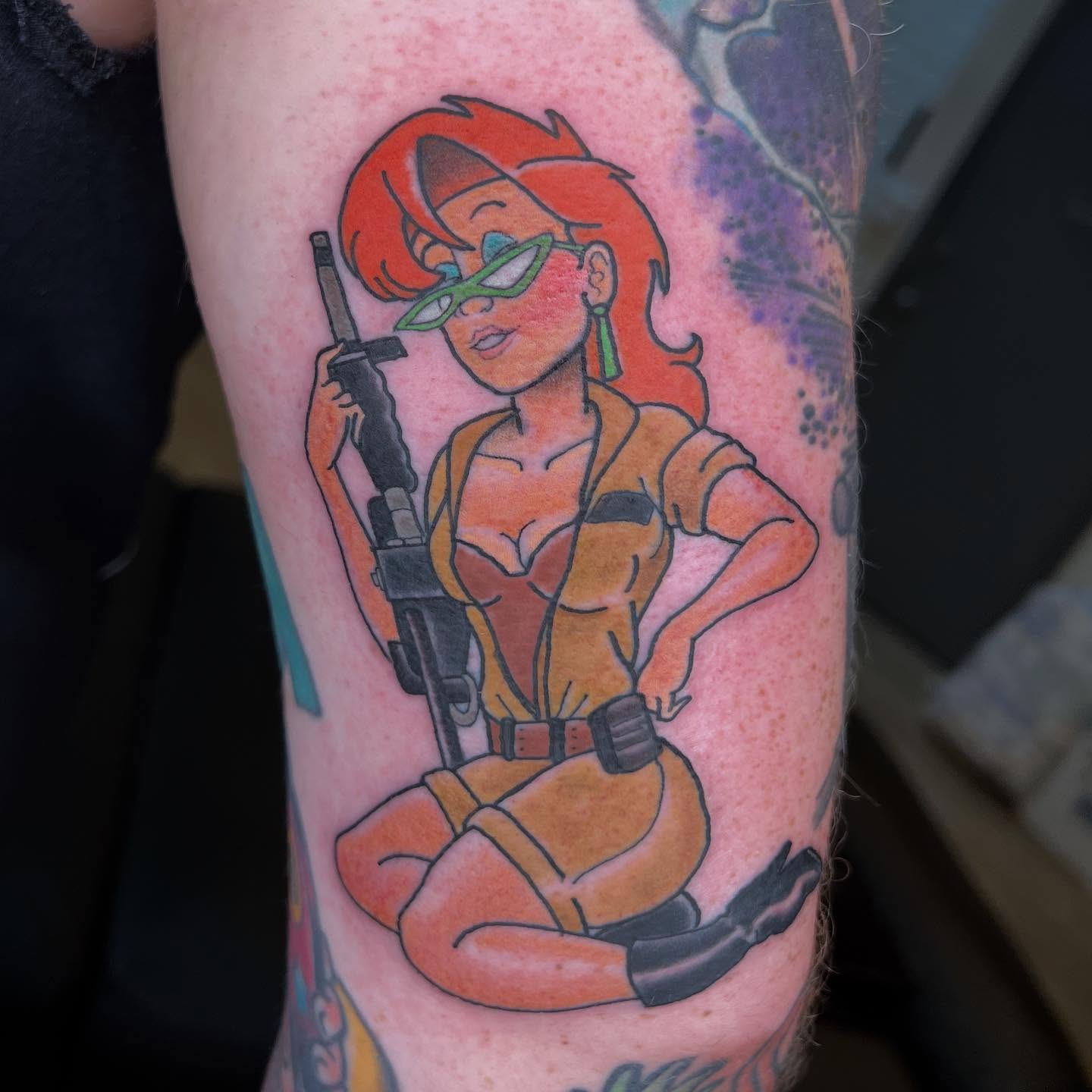 Red-haired character with gun new school tattoo on the forearm by Troy David Souders