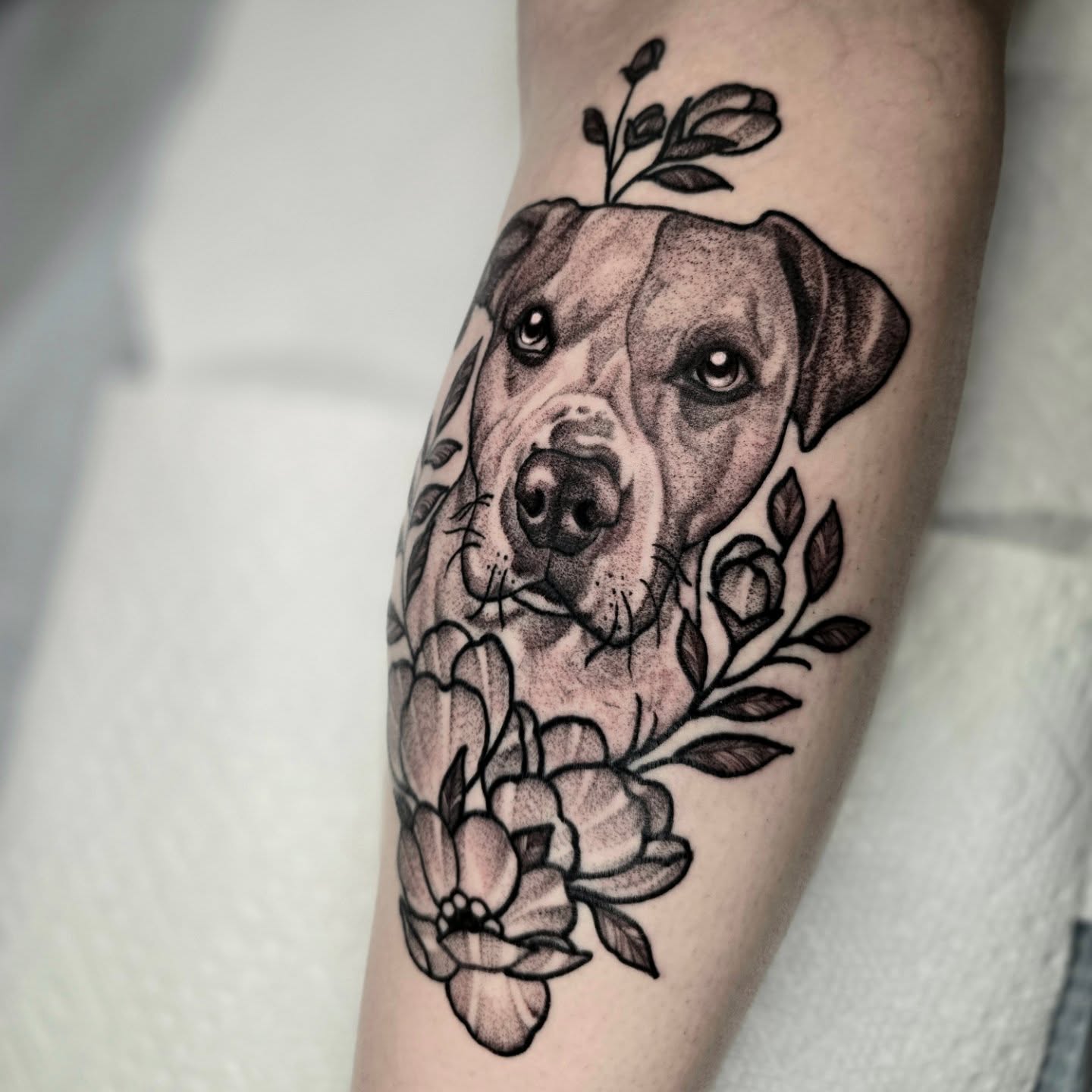 Dog with floral elements dotwork tattoo on the forearm by Adison Essig