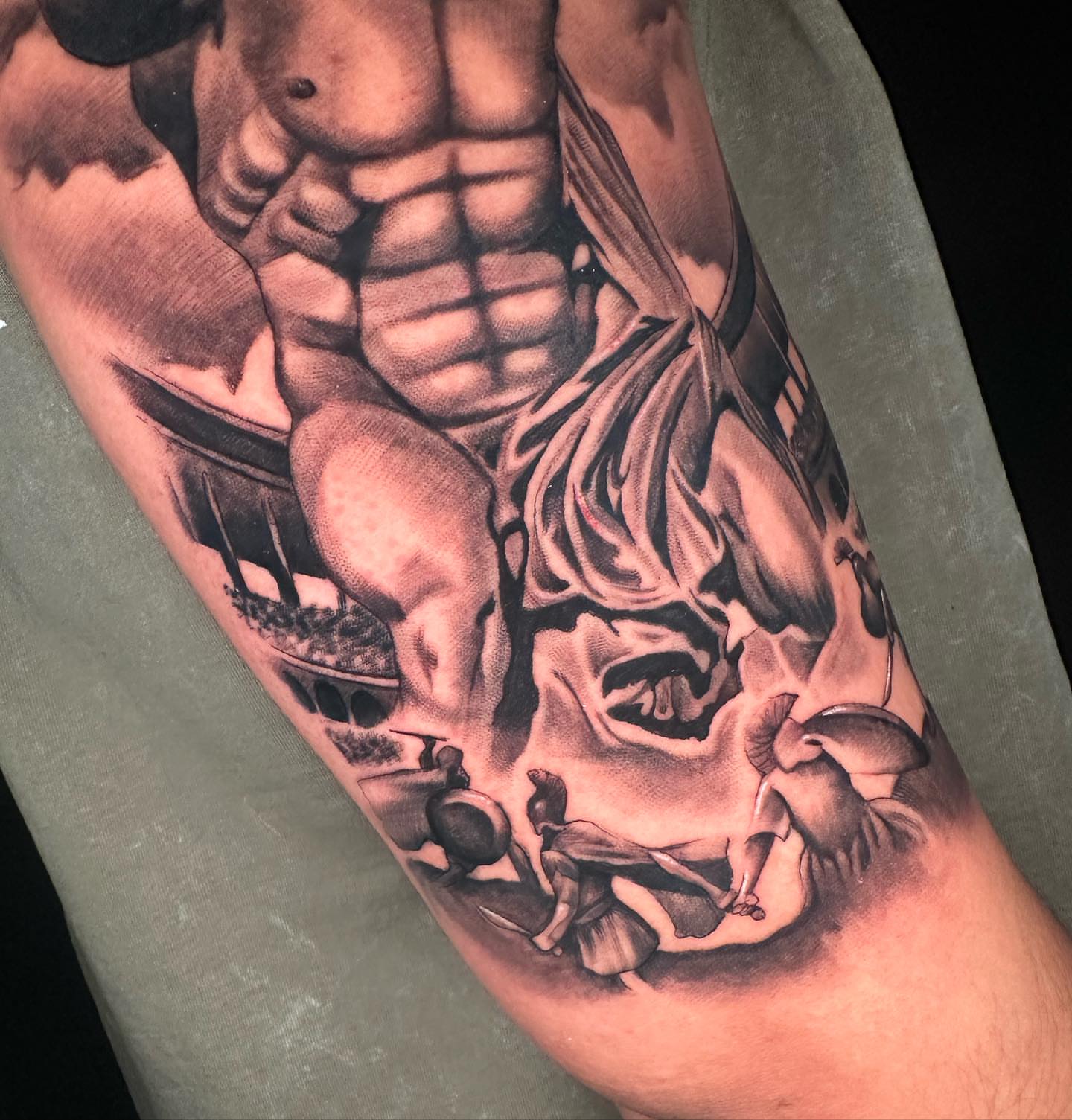 Muscular torso with mythological scene realism tattoo on the forearm by Angela Azure