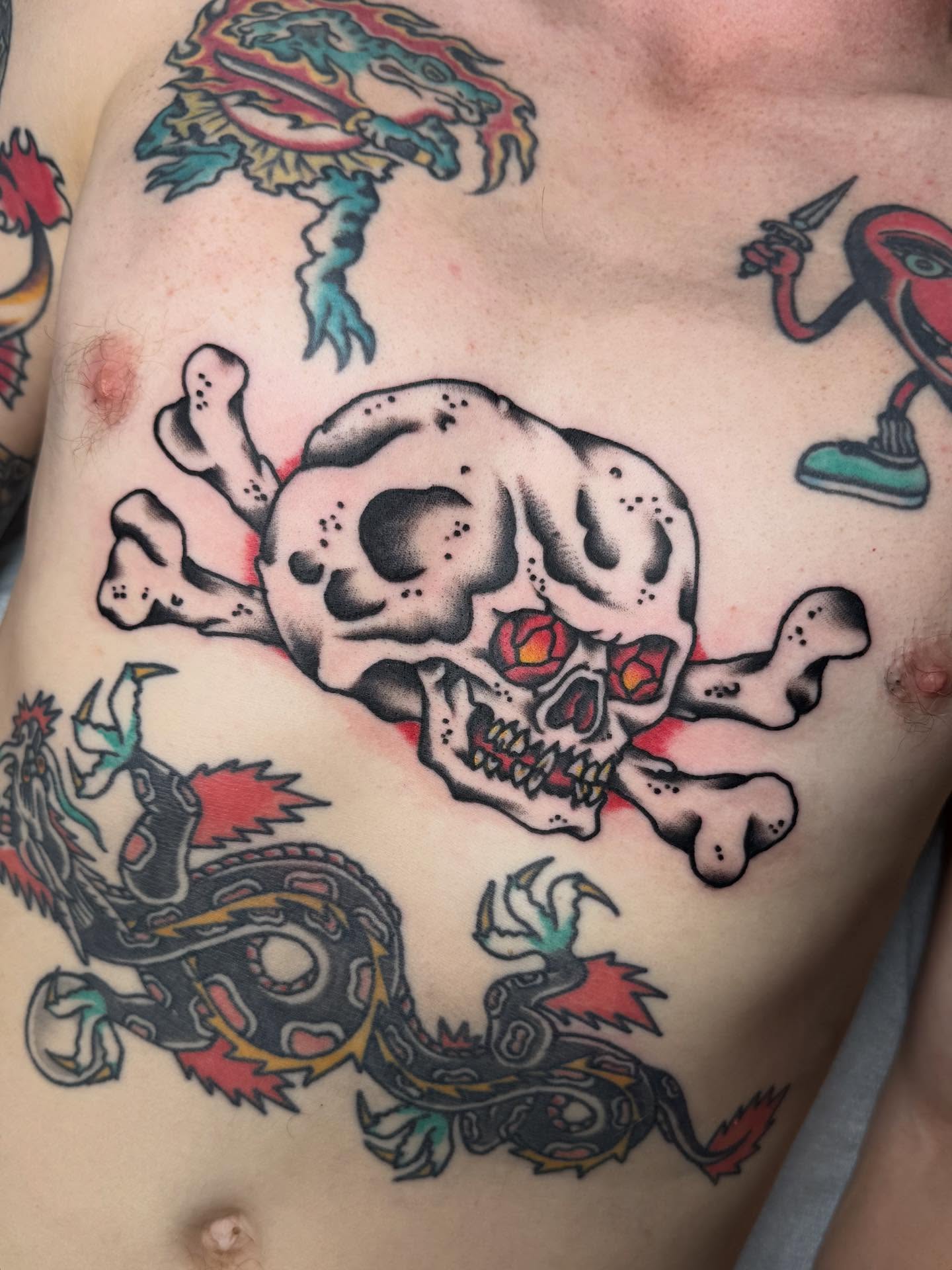 Skull and crossbones American traditional tattoo on the chest by Bill Crawford, Plymouth, Michigan