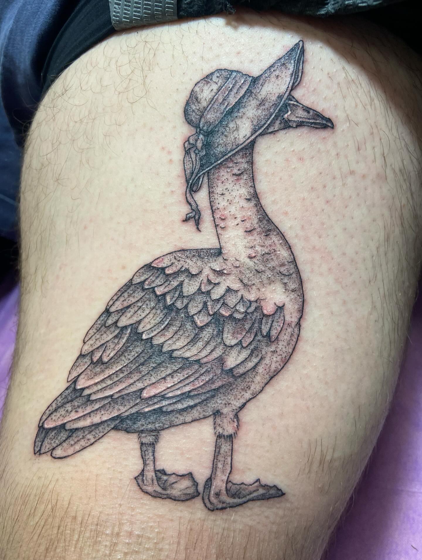 Goose wearing hat black and grey tattoo on the thigh by Dont Worry About It