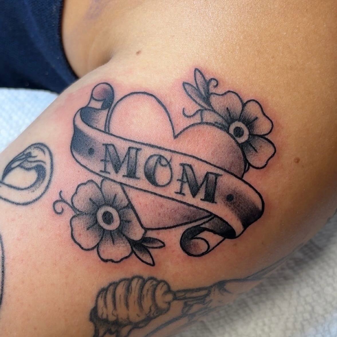 Heart with ribbon American traditional tattoo on the shoulder by Molly Dixon
