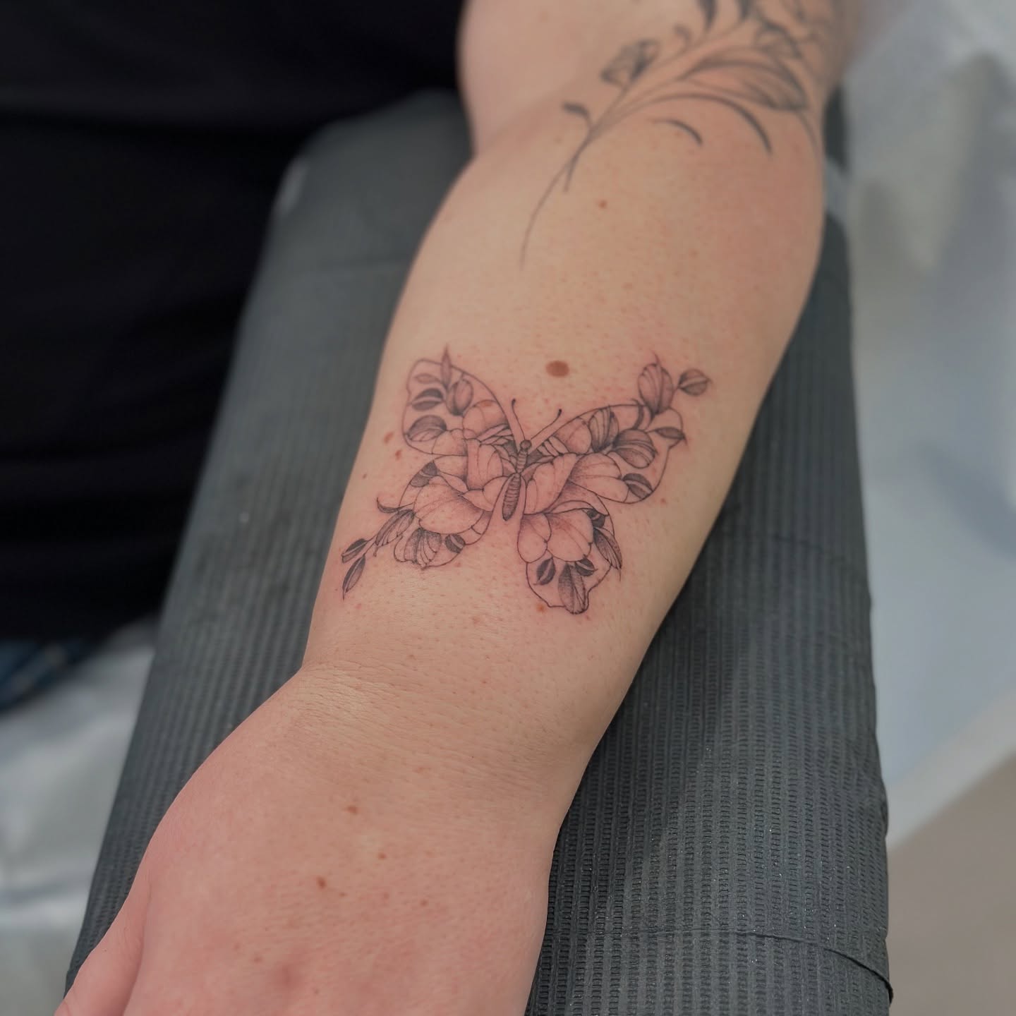 Butterfly and flowers black and grey tattoo on the forearm by ᴍɪᴄʜᴇʟʟᴇ, New York, New York