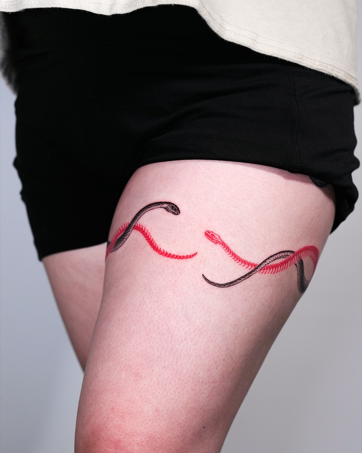 Snakes fine line tattoo on the thigh by Intat