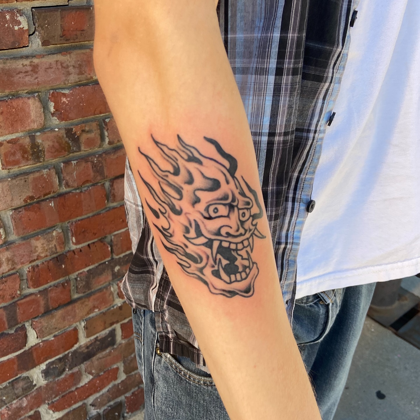 Flaming skull black and grey tattoo on the forearm by Anthony Robles