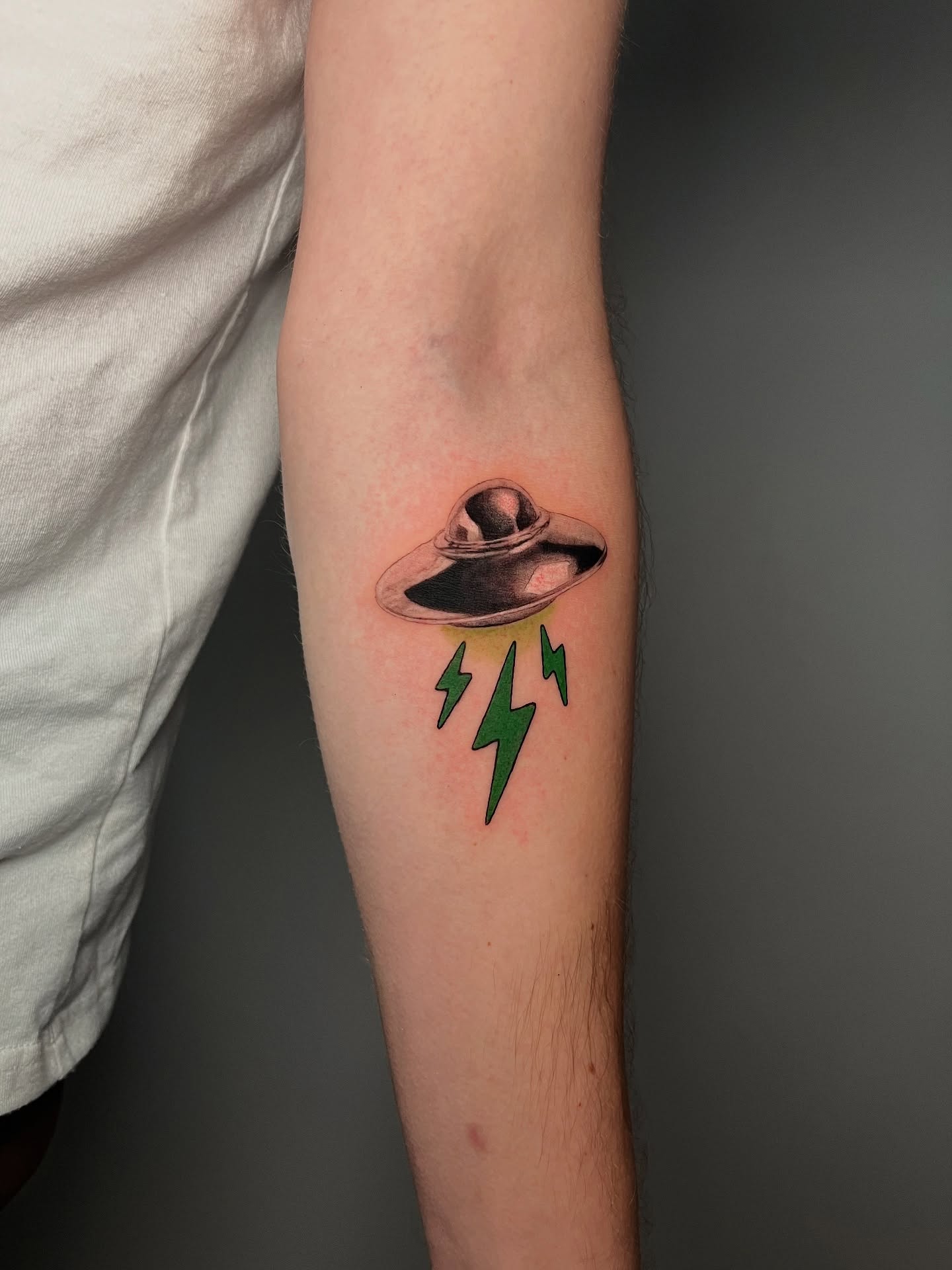 UFO with lightning bolts realism tattoo on the forearm by Jerm Lewis
