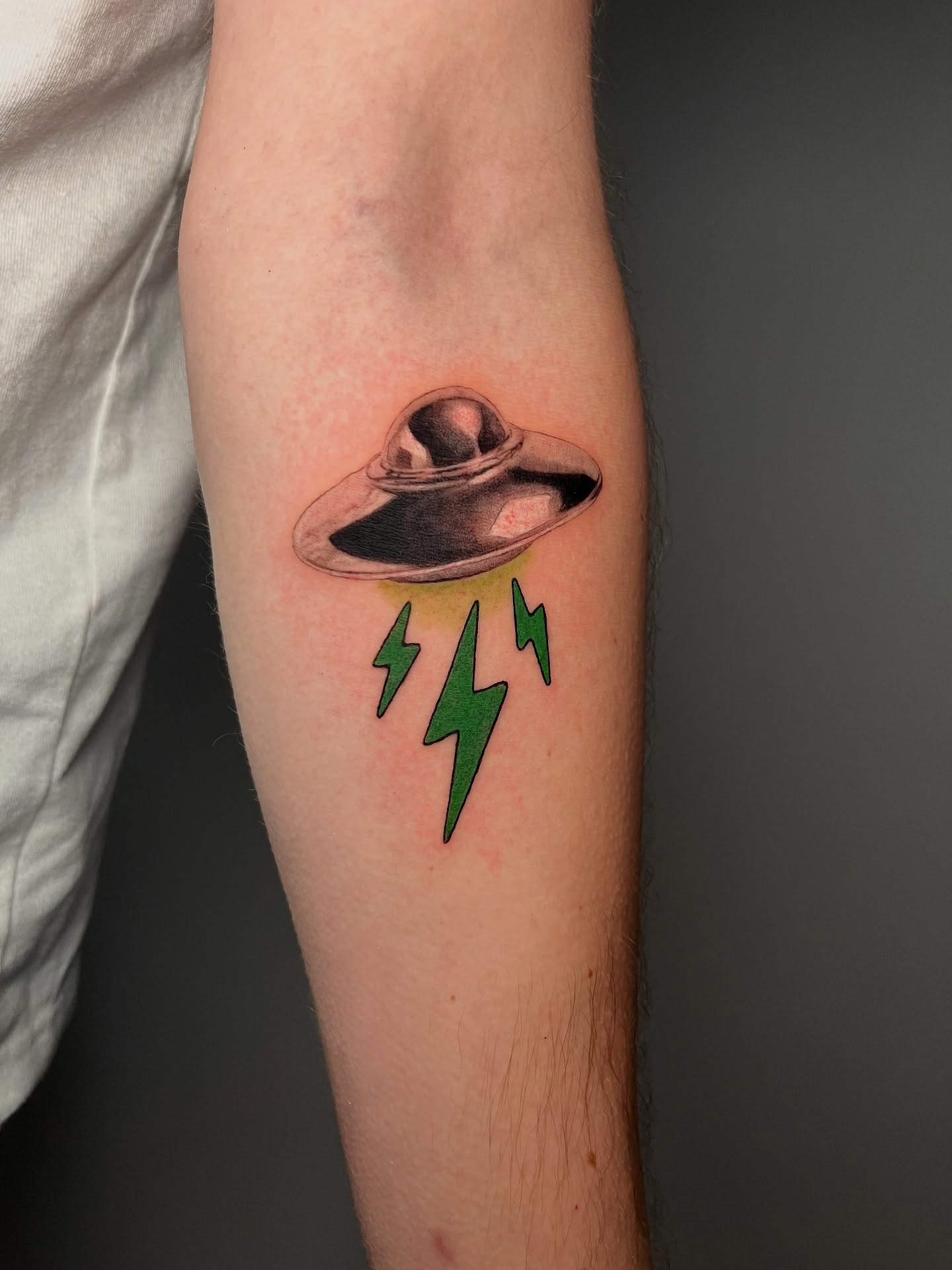UFO with lightning bolts realism tattoo on the forearm by Jerm Lewis