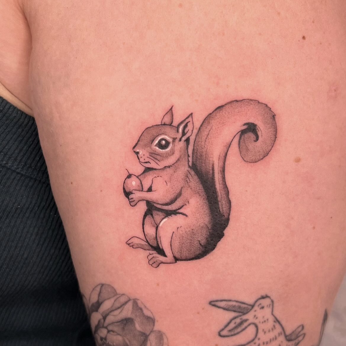 Squirrel black and grey tattoo on the upper arm by Robb Wilson
