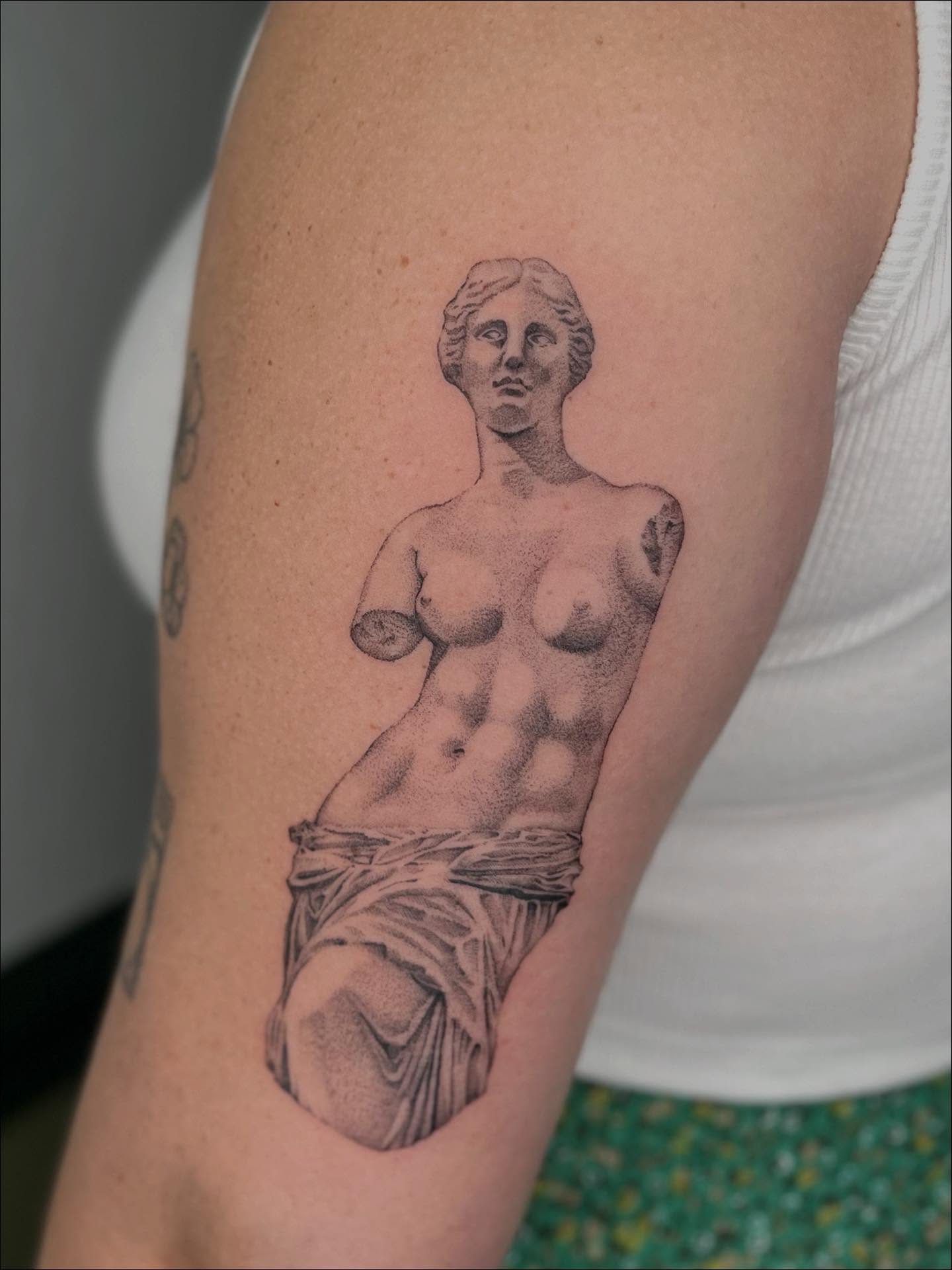 Statue realism tattoo on the upper arm by Ash F