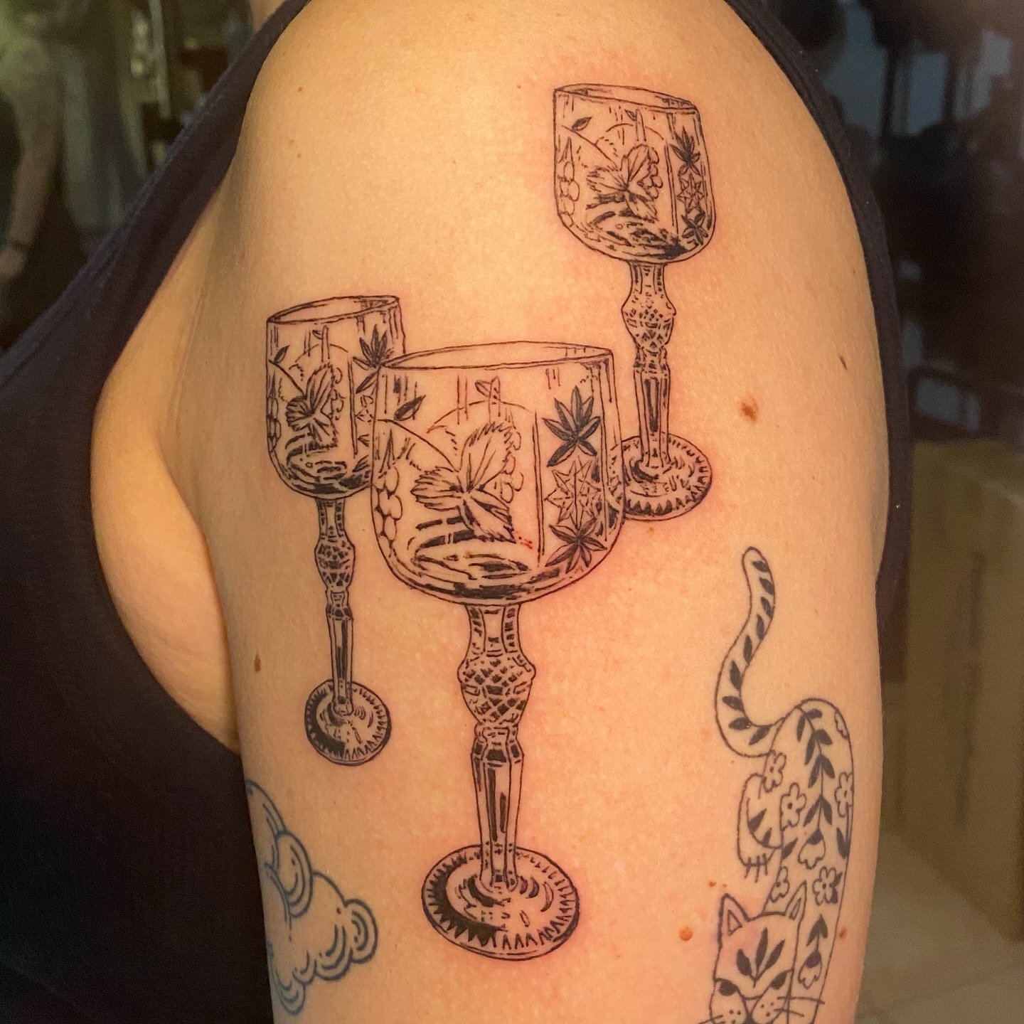 Wine glasses black and grey tattoo on the shoulder by Melissa Contreras