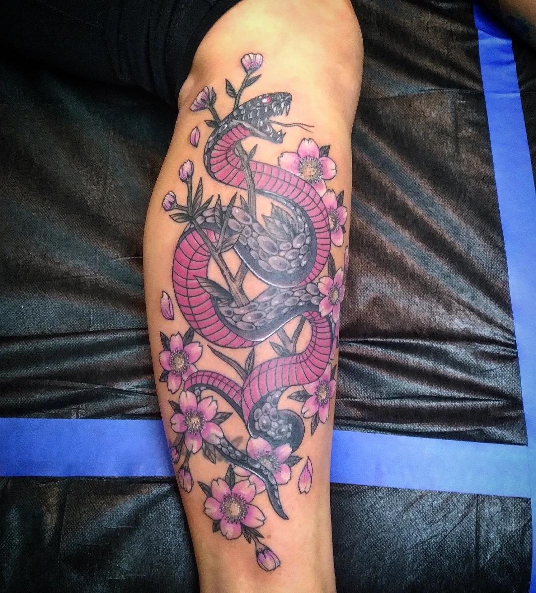 Snake and flowers American traditional tattoo on the forearm by Josh Sroga