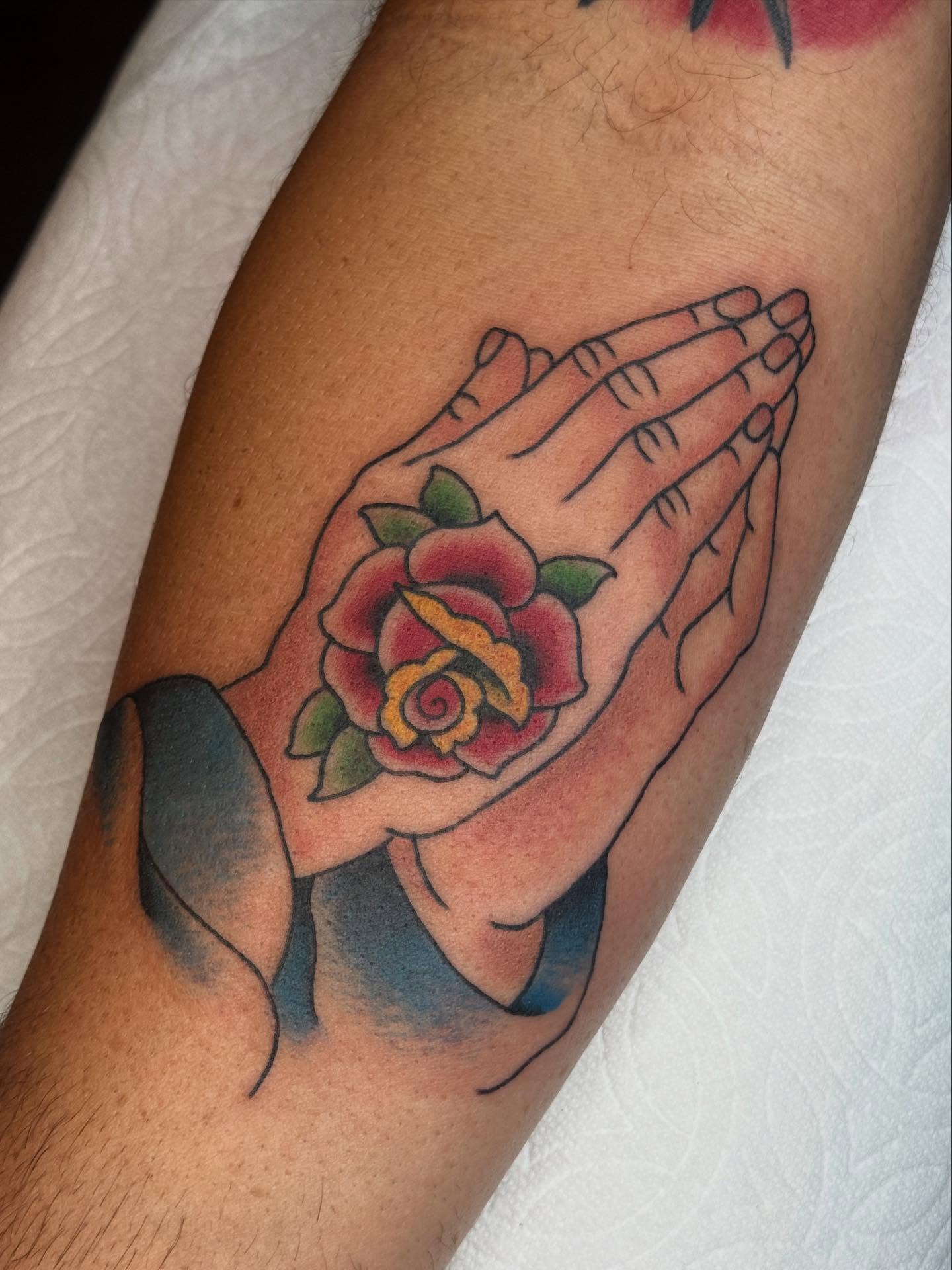 Praying hands with rose American traditional tattoo on the forearm by chloe jeanel estrada