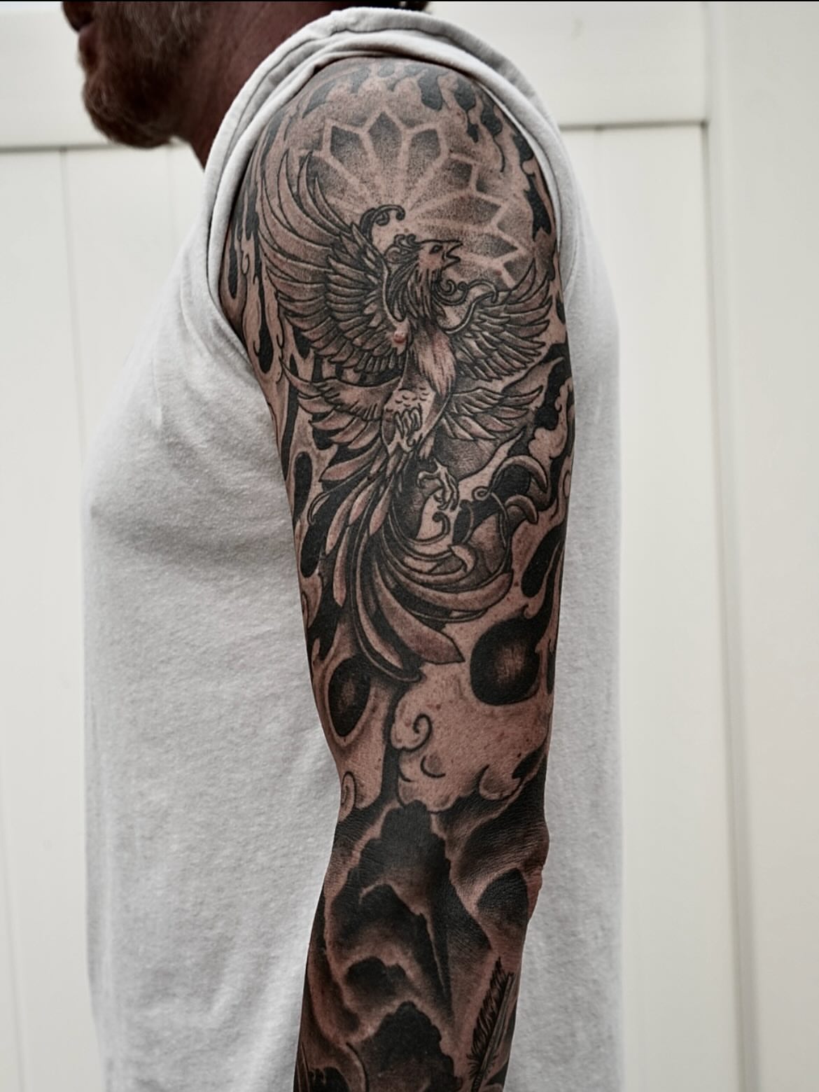Phoenix black and grey tattoo on the upper arm by Tattoo Artist