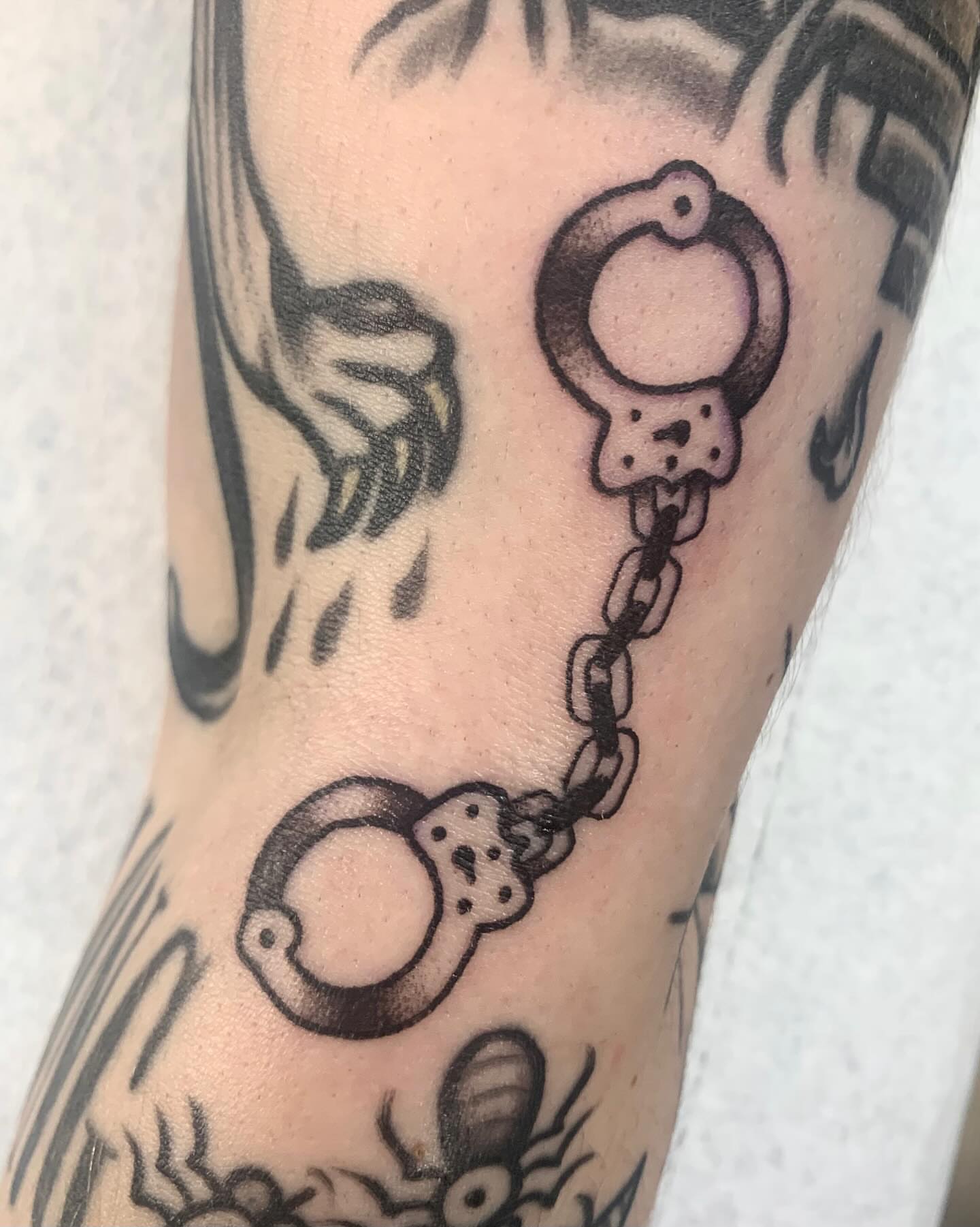 Handcuffs black and grey tattoo on the forearm by jay