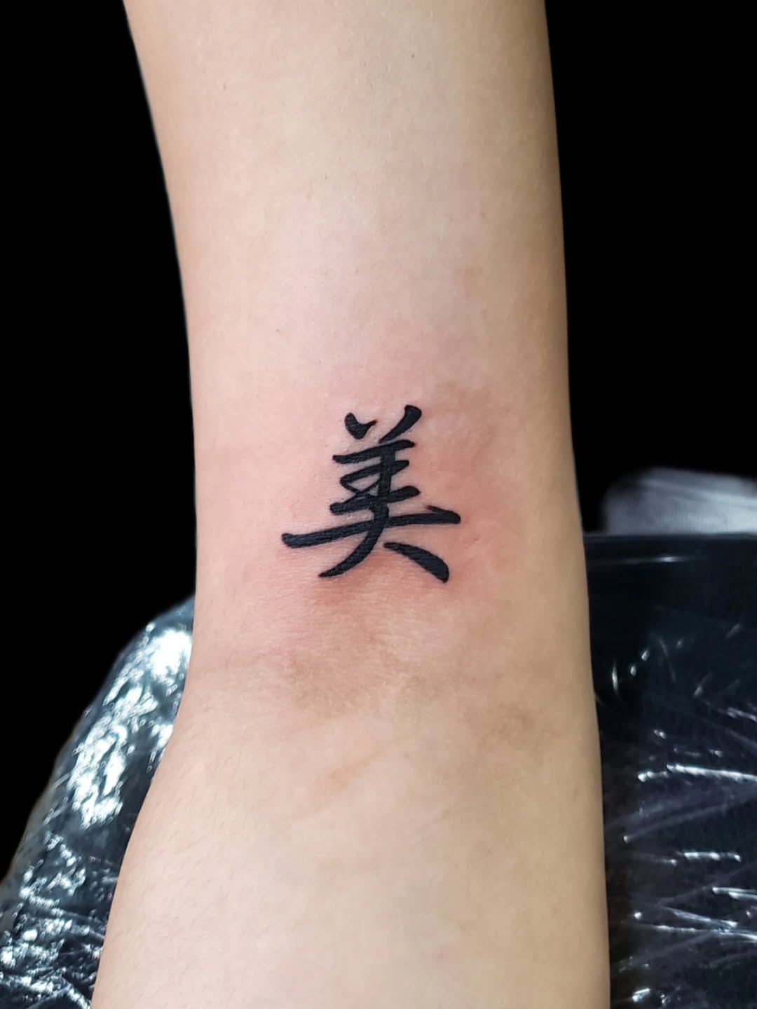 Chinese character 美 black and grey tattoo on the forearm by @youxg_guxxz