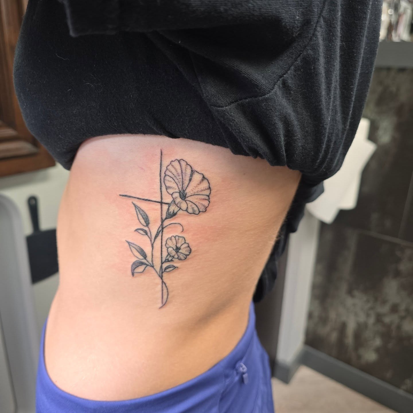 Flower and cross black and grey tattoo on the ribs by Karen Cain