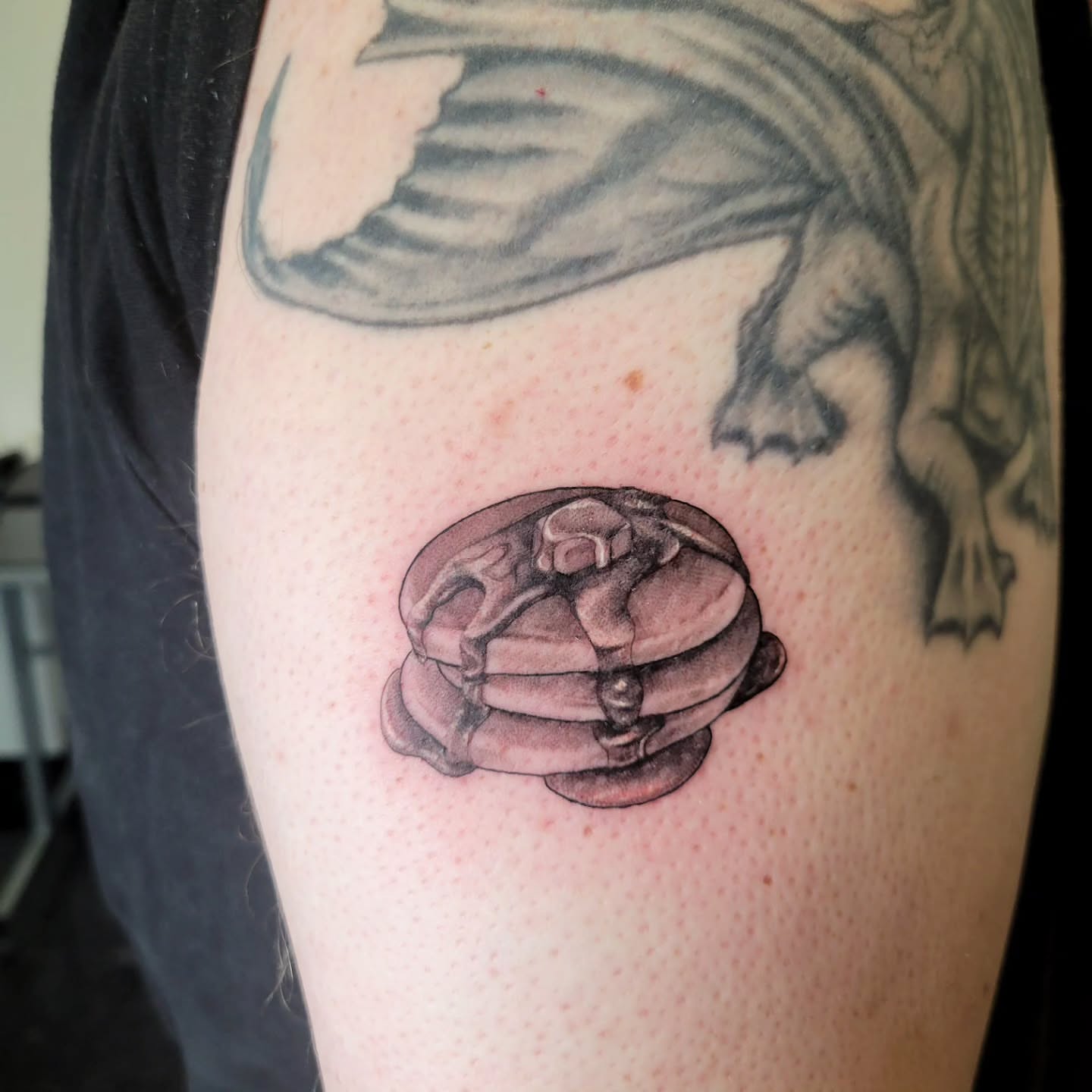 Pancake stack black and grey tattoo on the upper arm by Marina Cobb
