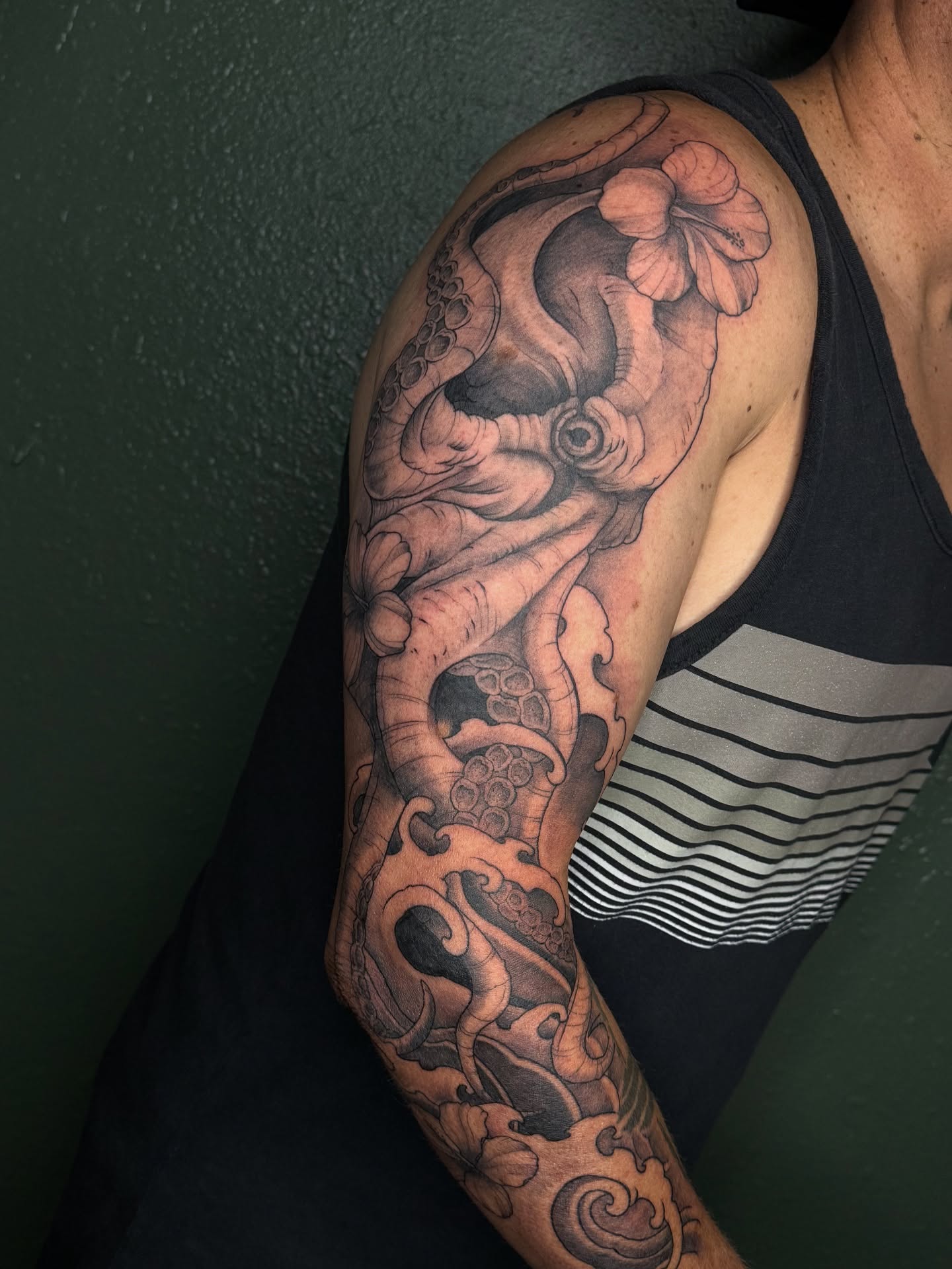 Octopus and hibiscus realism tattoo on the upper arm by Marcus
