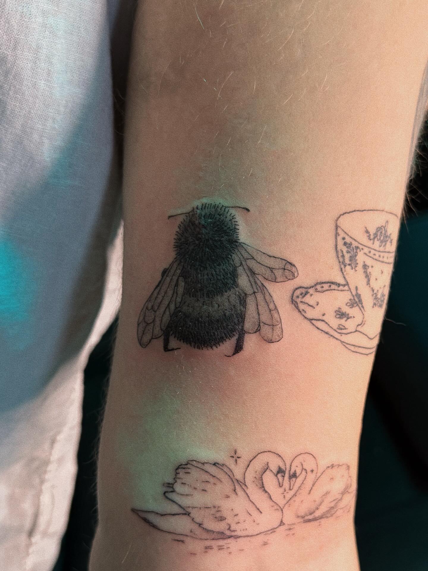 Bee and swans realism tattoo on the forearm by Paulina Vazquez