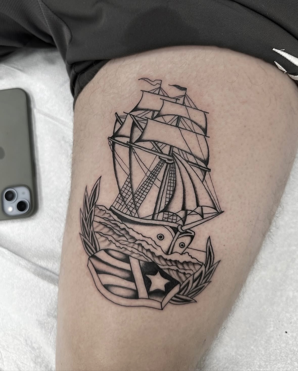 Ship and banner black and grey tattoo on the thigh by Nicholas Lee, San Francisco, California