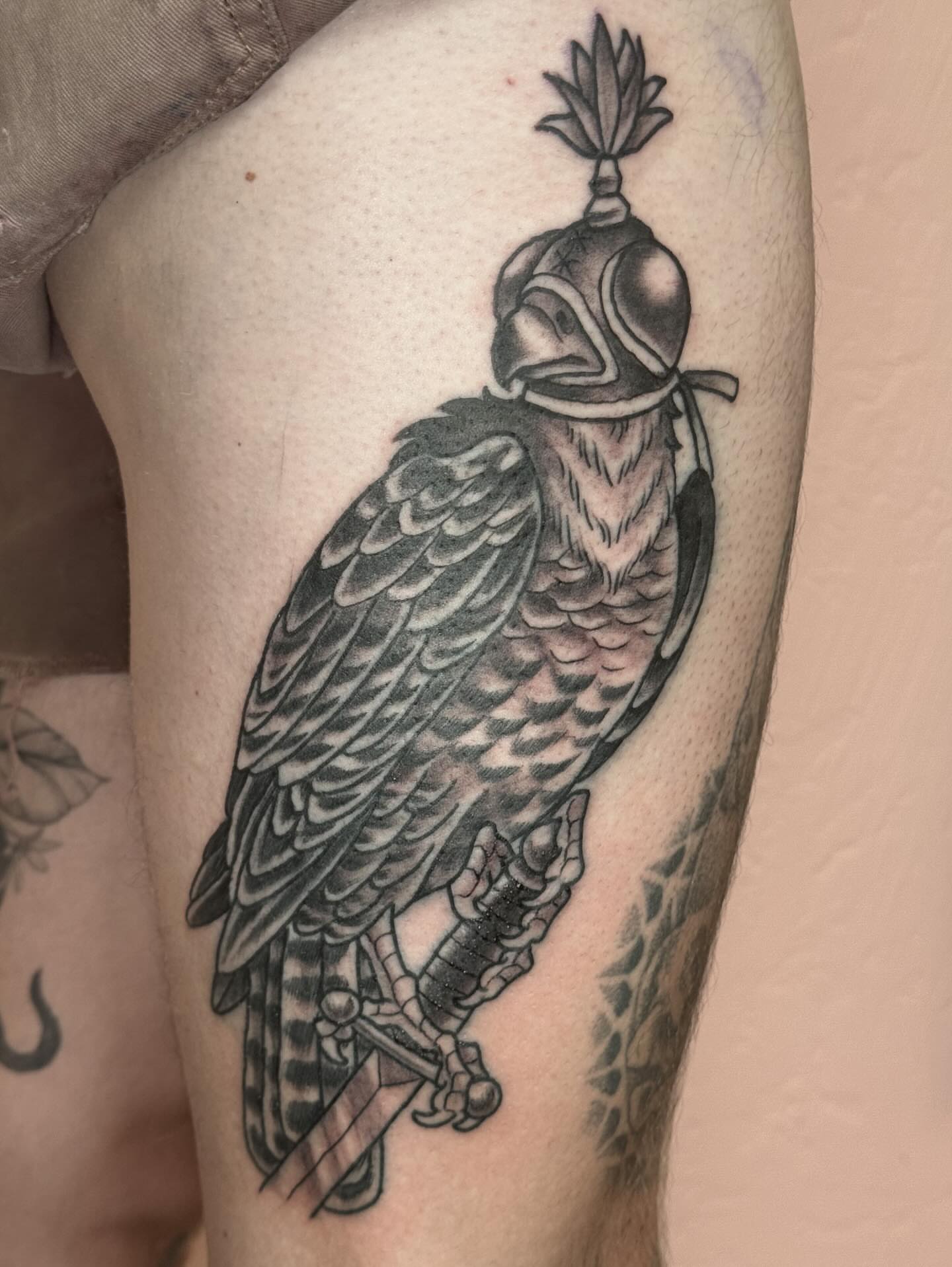 Hawk wearing helmet black and grey tattoo on the thigh by Bob Lackner