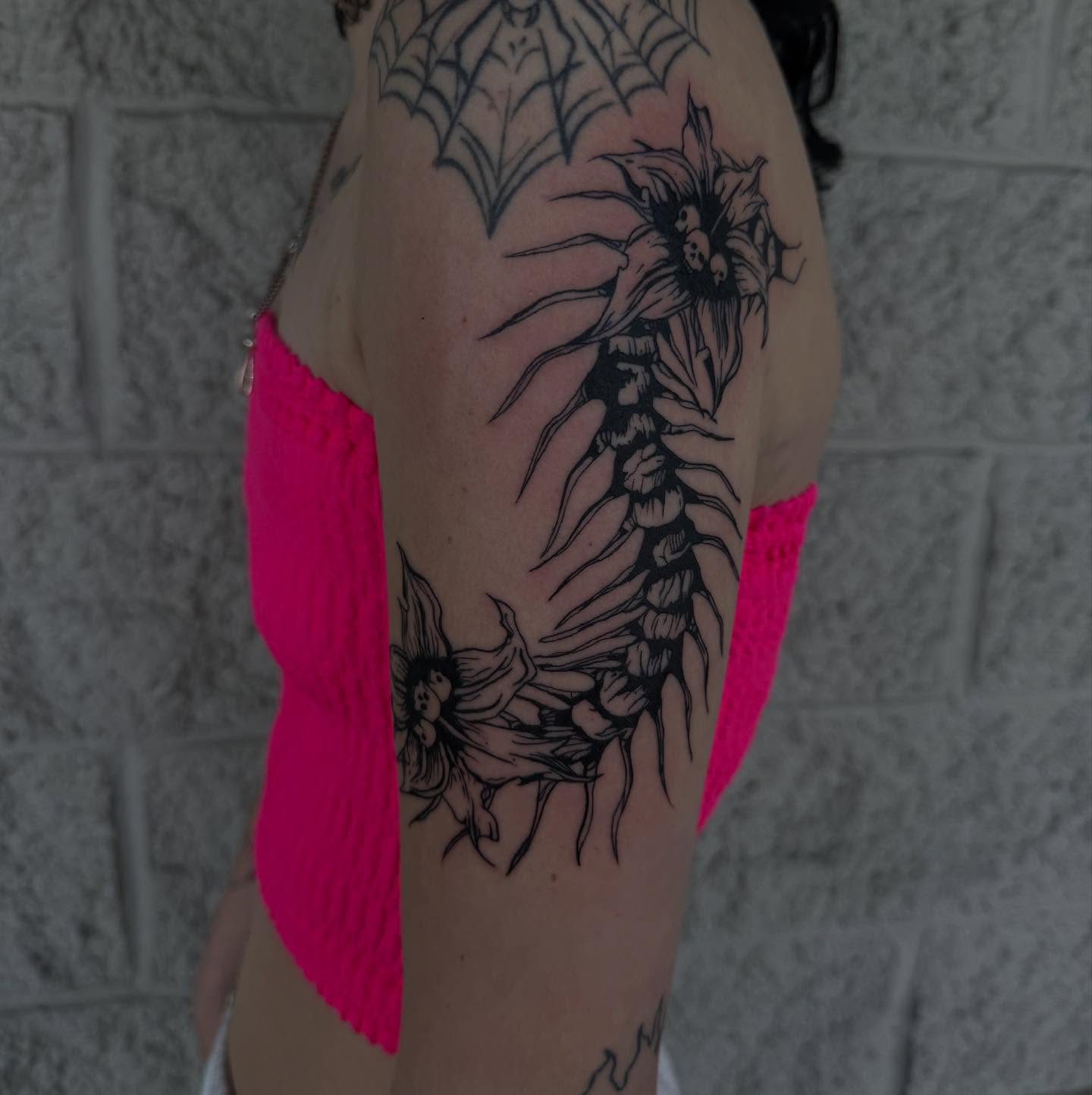 Spine and flowers black and grey tattoo on the upper arm by Kylee langford 🧿