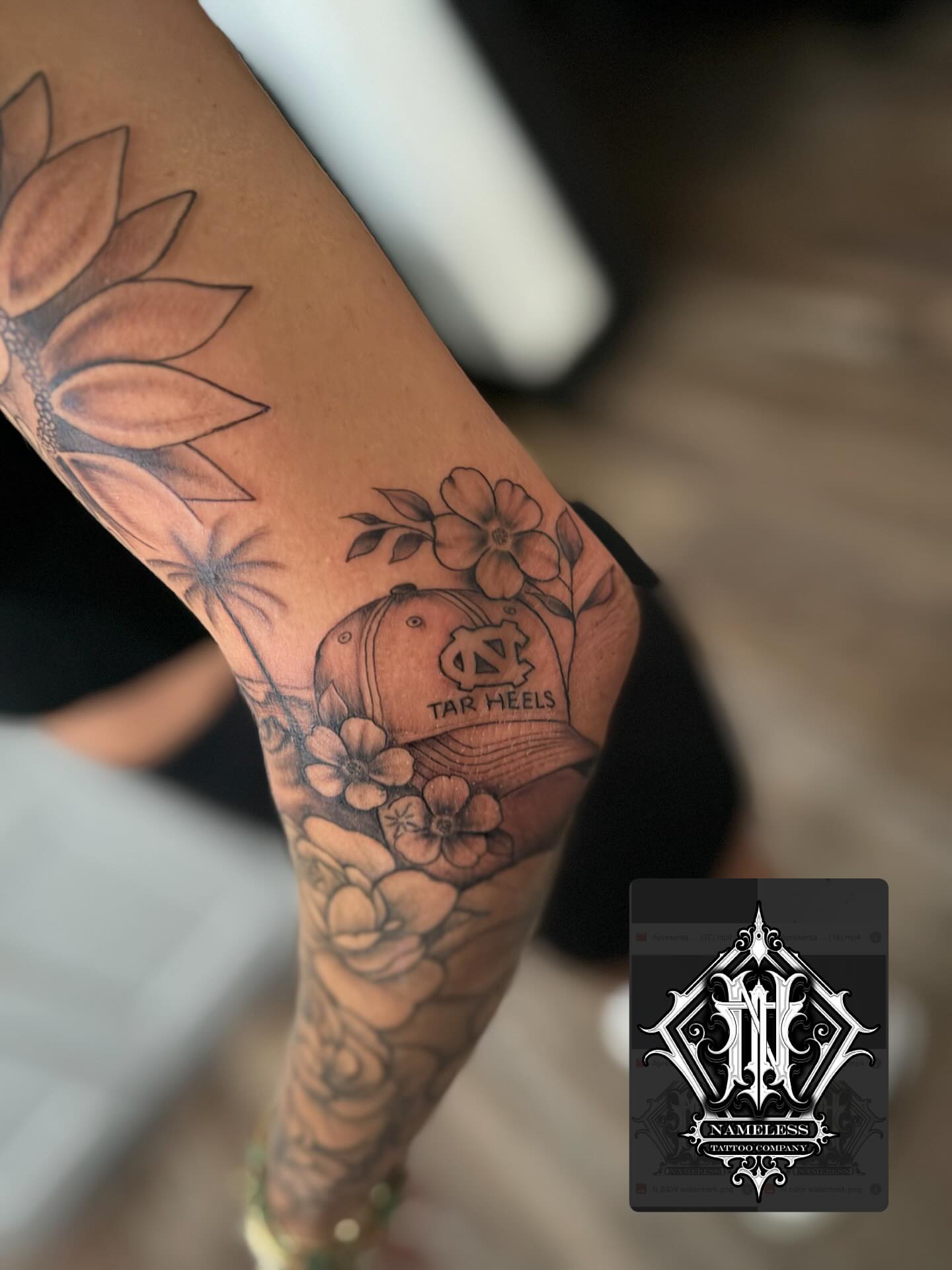 Tar heels cap with flowers black and grey tattoo on the forearm by AJ