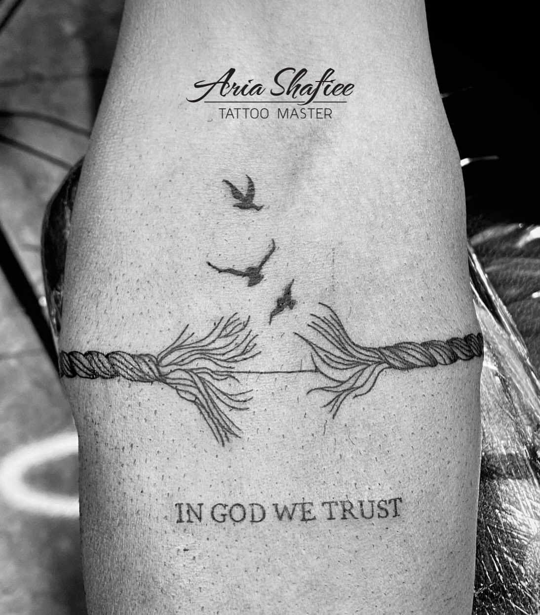 String black and grey tattoo on the forearm by Aria Shafiee