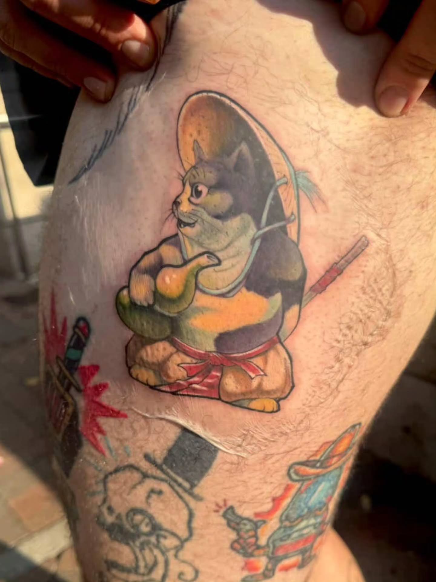 Cat wearing sombrero and holding cactus American traditional tattoo on the thigh by Justin Byrd, Kansas City, Missouri