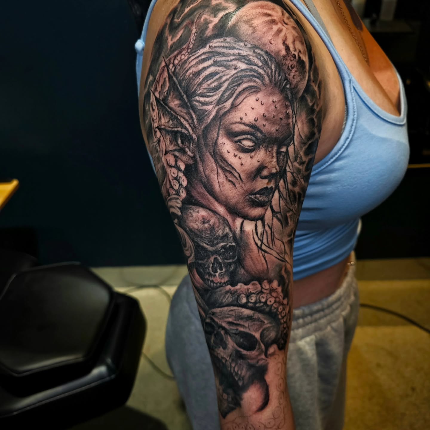 Woman with skulls realism tattoo on the upper arm by Drew King
