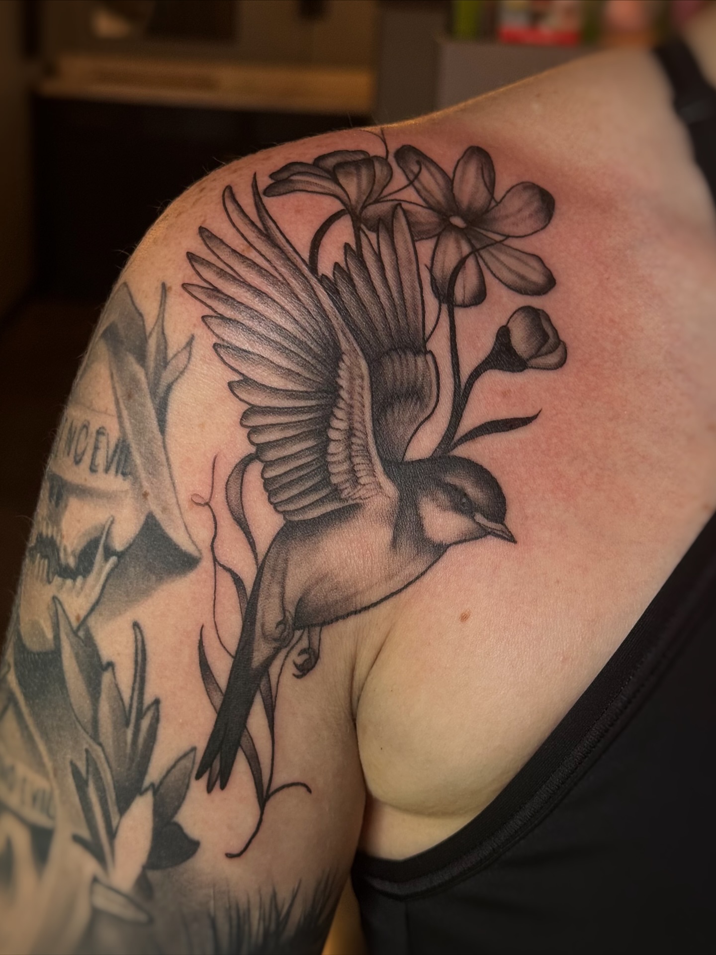 Bird and flowers black and grey tattoo on the shoulder by Lily Bejarno
