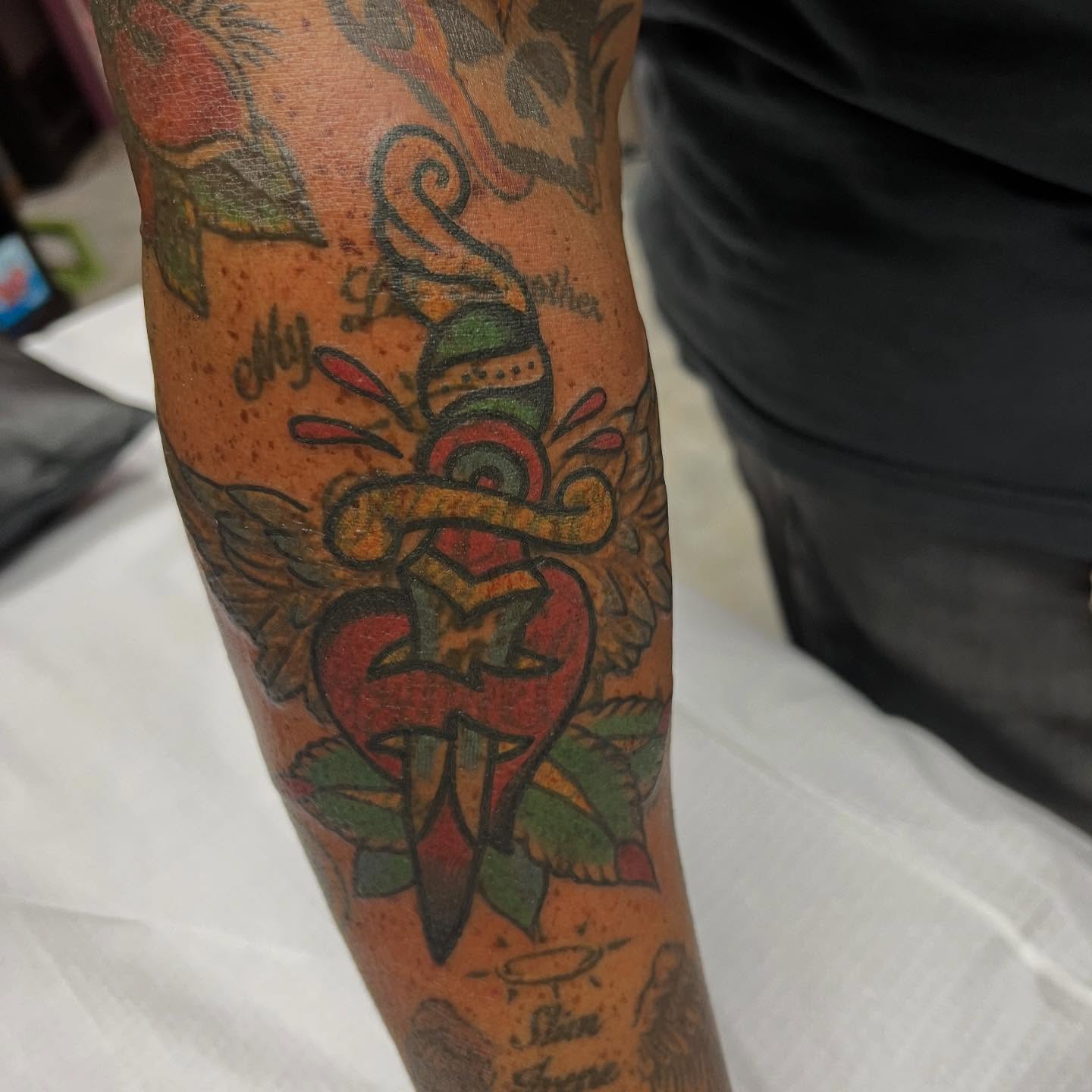 Heart with dagger American traditional tattoo on the forearm by doodle