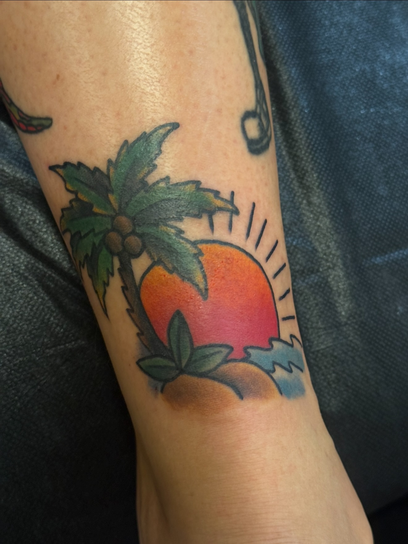 Palm tree and sunset American traditional tattoo on the forearm by Candi Kinyōbi
