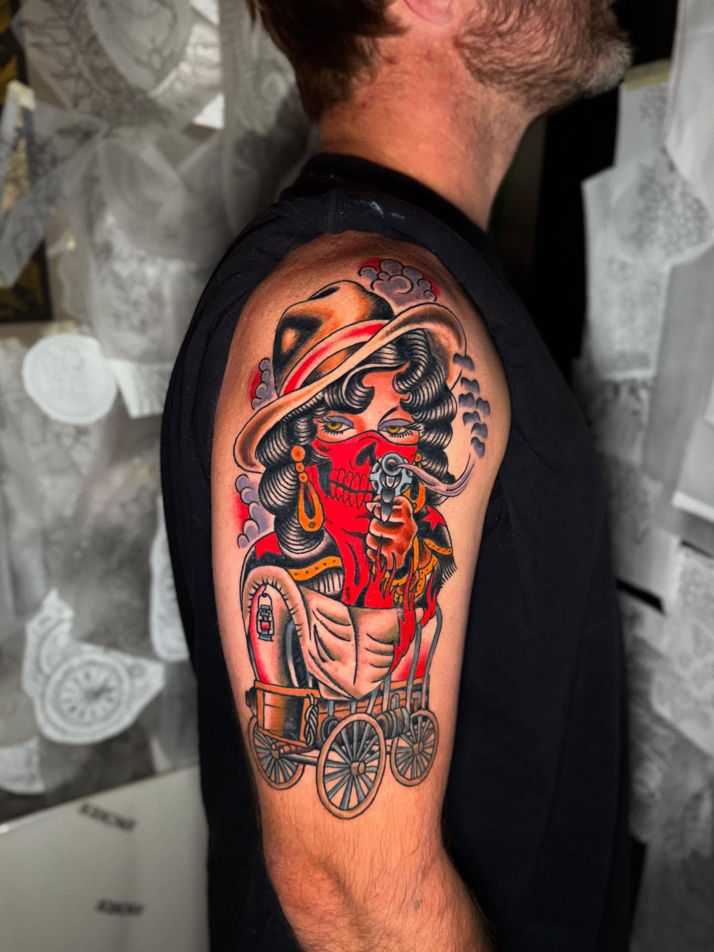 Cowgirl on wagon American traditional tattoo on the upper arm by Seth Walker