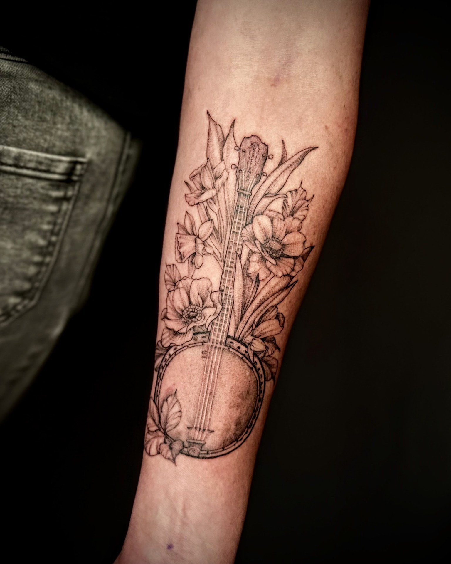 Banjo and flowers black and grey tattoo on the forearm by Giovanna Kline