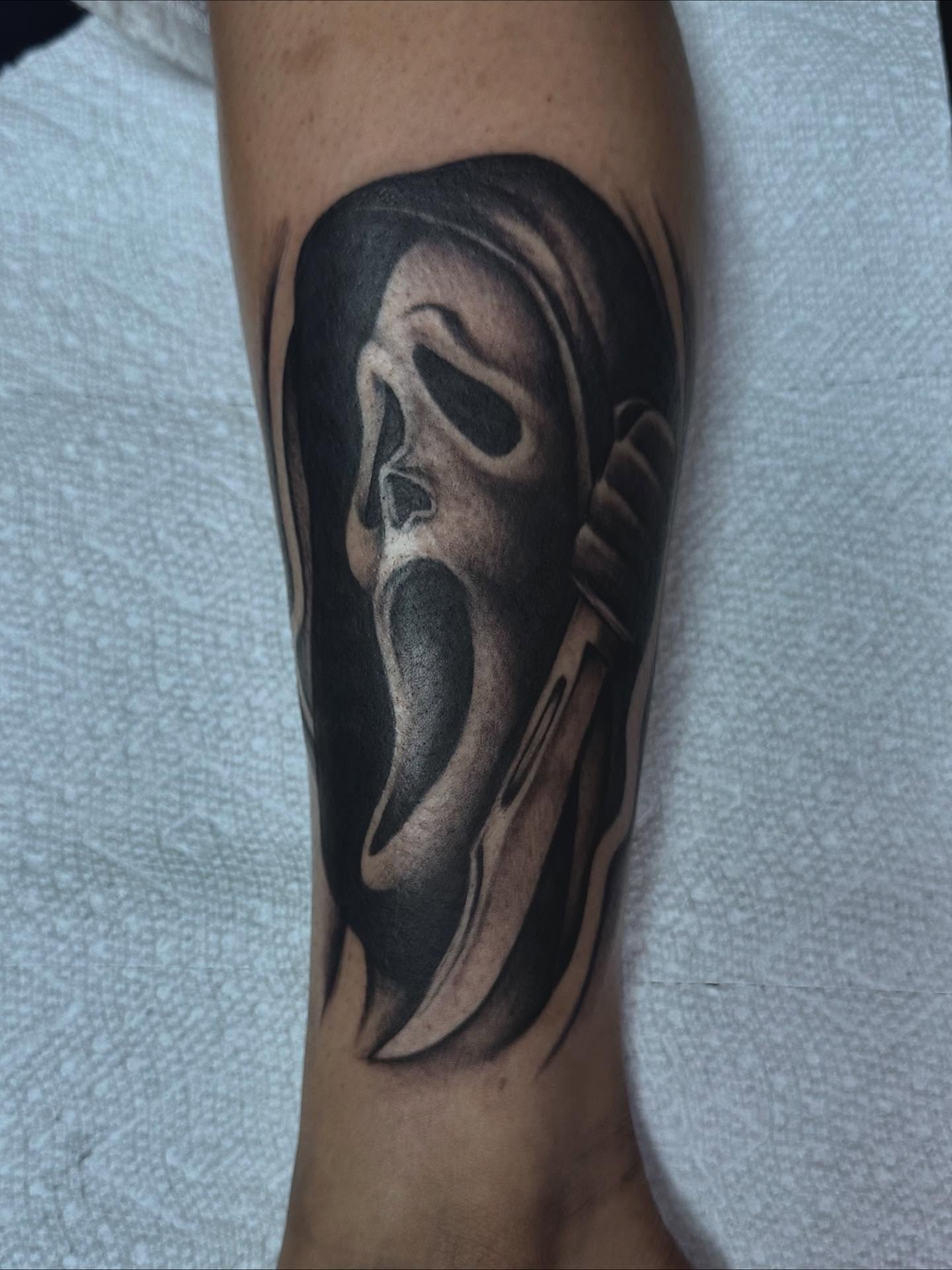 Scream mask black and grey tattoo on the forearm by Colby McClain
